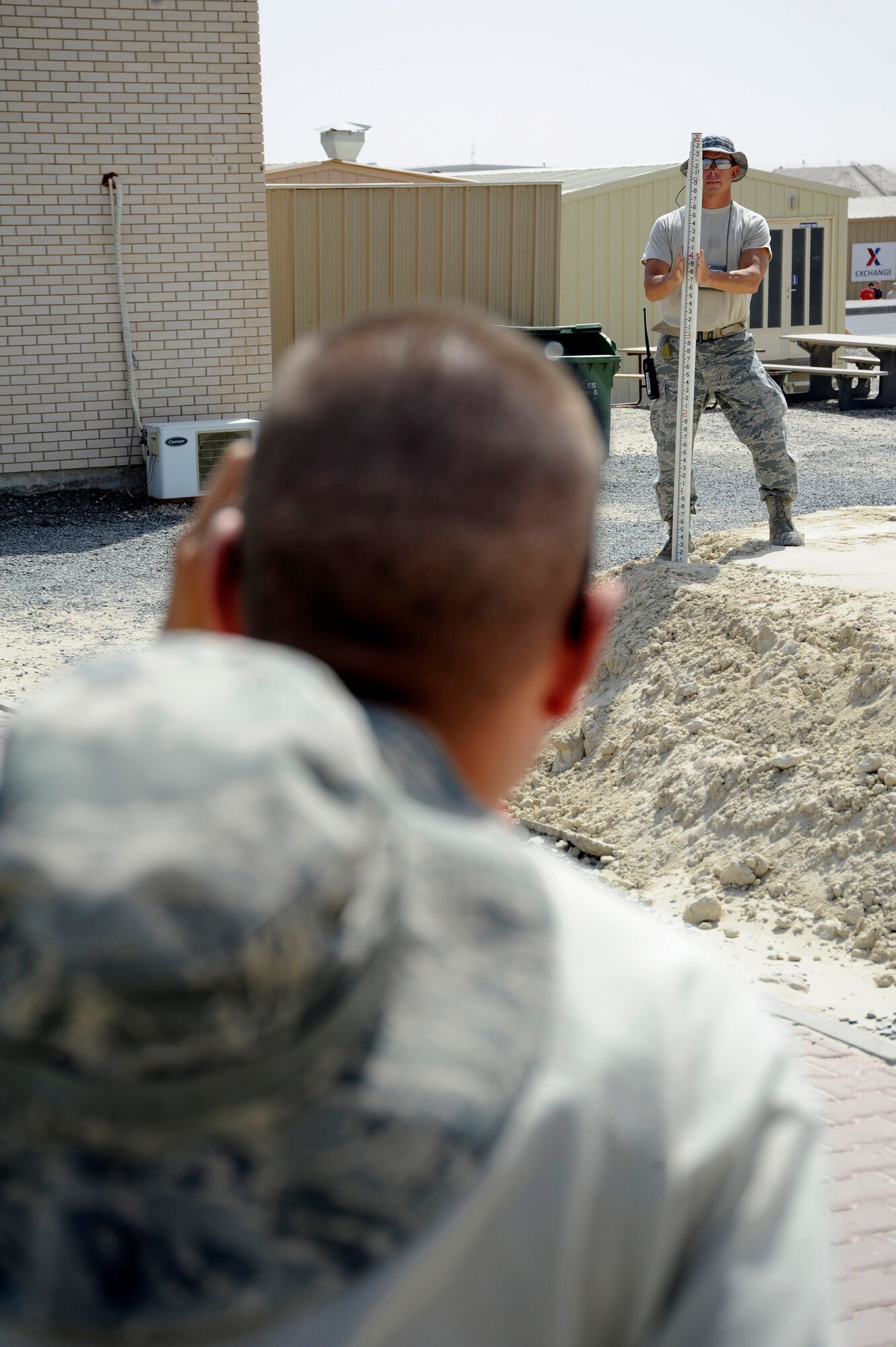Senior Airman Adam Walden, 386th Expeditionary Civil Engineer Squadron, holds a Philadelphia Rod while Tech. Sgt. Mark Ondersma, 386th ECES, looks through an auto leveler here, July 29, 2013. Walden and Ondersma are both heavy equipment operators. They are taking measurements to ensure the base material is level all around the site before placement of a new building. Ondersma, a native of Hudsonville, Mich. is deployed out of the 110th Airlift Wing, Battle Creek, Mich., Air National Guard unit. Walden is also a member of the 110th A.W. and is a native of Clinton Mich. (U.S. Air Force photo by Master Sgt. Christopher A. Campbell)