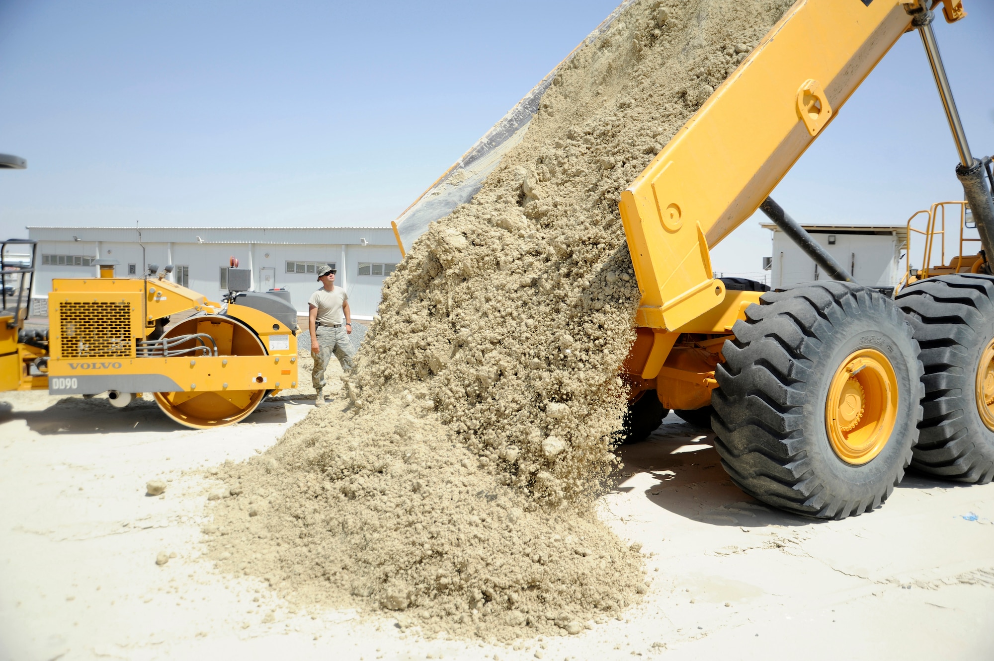 Tech. Sgt. Mark Ondersma, 386th Expeditionary Civil Engineer Squadron, heavy equipment operator, watches as Tech. Sgt. Phillip Biwer, 386th ECES, heavy equipment operator, operates a Volvo 30-ton dump truck here, July 24, 2013. Ondersma directs Biwer where to dump the gatch at the future site of a new building. Gatch is a sand and gypsum mix used under all buildings here; it is the equivalent to quick concrete. Ondersma, a native of Hudsonville, Mich. is deployed out of the 110th Airlift Wing, Battle Creek, Mich., Air National Guard unit. Biwer, a native of Plainfield Ill. is deployed out of the 110th Airlift Wing, Battle Creek, Mich., Air National Guard unit. (U.S. Air Force photo by Master Sgt. Christopher A. Campbell)