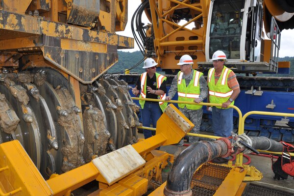 Bjoern Hoffman, left, Bauer Foundation Corporation project manager explains the Bauer MC 128 Hydrocutter to Maj. Gen. Michael Walsh, center, deputy commanding general, Civil and Emergency Operations, U.S. Army Corps of Engineers during his July 31, 2013 visit to Nashville District’s Center Hill Dam. Jimmy Waddle, District Engineering and Construction Division chief is at right. The Hydrocutter, largest of its type in the world, which Bauer built specifically for the Center Hill Dam Seepage Rehabilitation project, cuts an approximate 10.5 X 7.25-foot element for the encasement wall in the embankment. Bauer will drill down 300 feet from the top of the earthen portion of the dam, through the encasement wall and up 130 feet into rock and construct concrete piles and panels to form the barrier over the next two years, according to Linda Adcock, Nashville District project manager. (USACE photo by Fred Tucker)