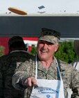 Maj. Gen. Michael Carey, 20th Air Force commander, tosses a freshly-cooked pancake to a boy scout who is waiting to catch it July 24, 2013, during a free breakfast open to the public as part of the annual Cheyenne Frontier Days festivities. It is traditional for leadership at F.E. Warren Air Force Base, Wyo., to help cook some of the thousands pancakes served. (U.S. Air Force photo by R.J. Oriez) 