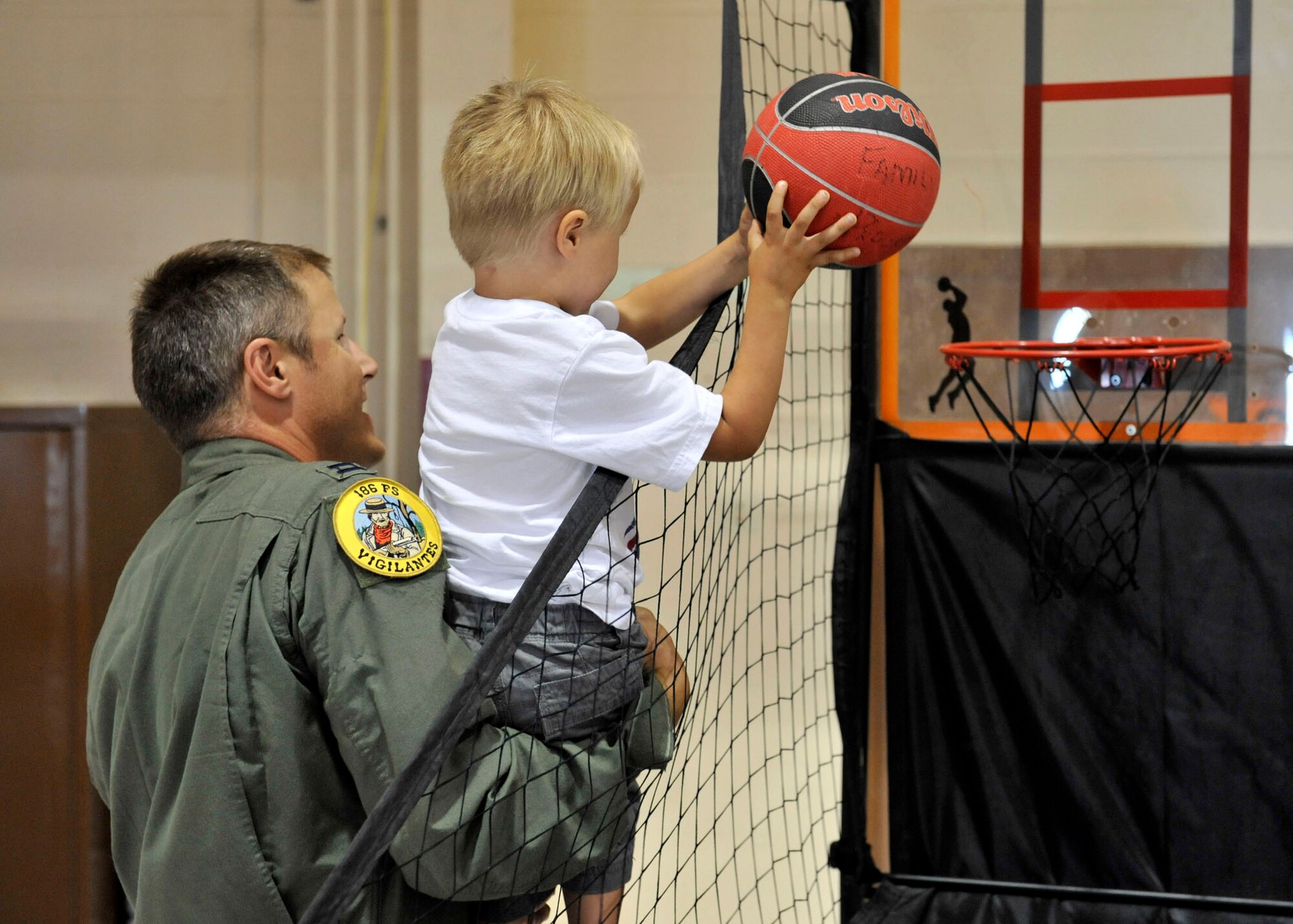 Capt. Clay Bird, 120th Fighter Wing member, helps a young basketball player sink a basket during the Montana Air National Guard Family Day on Aug. 11, 2012. (U.S. Air Force photo/John Turner)
