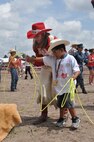 Kaci Malmborg, the 2013 Cheyenne Frontier Days Lady-in-Waiting, aids a child with his lassoing technique July 24, 2013, during the Cheyenne Frontier Days Challenge Rodeo event held in Frontier Park, Cheyenne, Wyo. (U.S. Air Force photo by Airman 1st Class Brandon Valle)