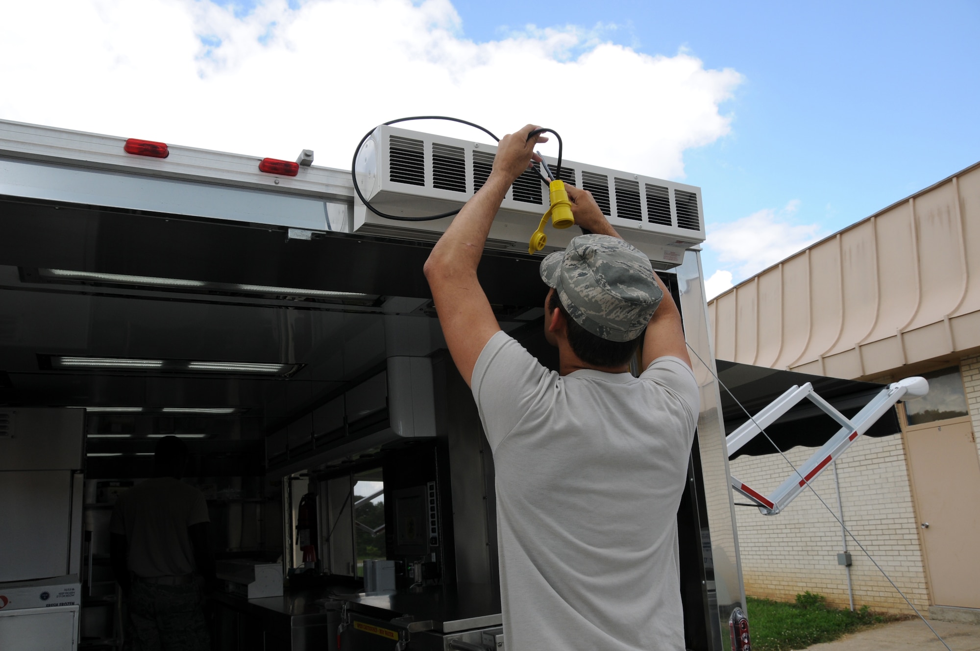 U.S. Air Force Senior Airman Christian King, Force Support Squadron, 123d Airlift Wing, Louisville, Kentucky, connects an “air curtain” to keep insects out of the Disaster Response Mobile Kitchen Trailer (DRMKT) July 15 at ‘Hope of Martin’ Innovative Readiness Training held at Martin Middle School in Martin, Tenn. (U.S. Air National Guard photo by Master Sgt. Carlos J. Claudio/Released).