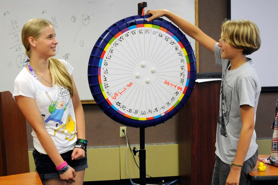 HANSCOM AIR FORCE BASE, Mass. -- Taylor Andrews (left) and Alberto Weissgarber spin a wheel to determine who has the first showcase pick at the Airman and Family Readiness Center July 29 during a money management workshop. Similar to the popular television game show, the Price is Right, the game illustrates how much things cost as part of the budgeting section of the workshop. The teens are participating in a four-week workshop through the Youth Center. (U.S. Air Force photo by Linda LaBonte Britt)