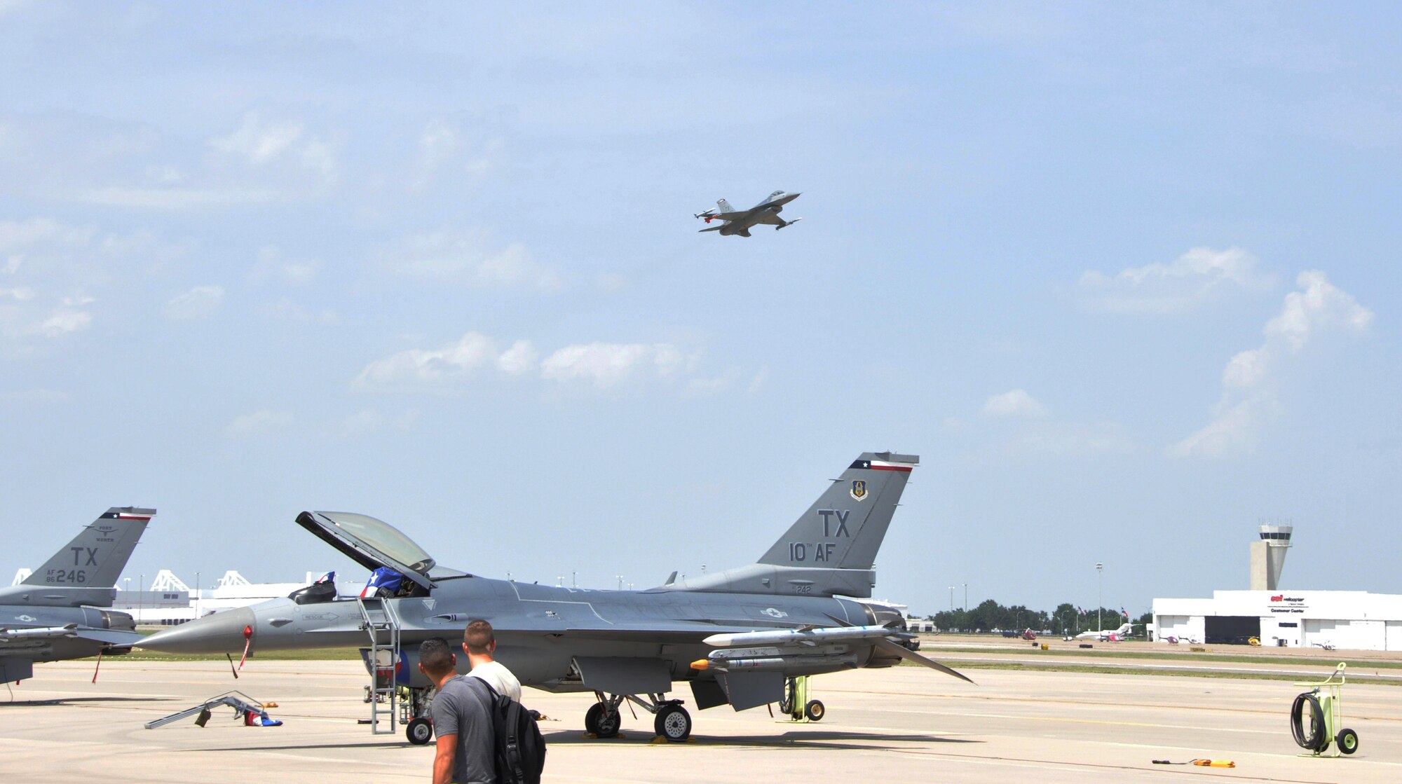 Two members of the 301st Maintenance Group look on as an F-16 takes off from Alliance Airport. Flight operations began July 31 as the runway at Naval Air Station Fort Worth Joint Reserve Base, Texas, is closed to allow much-needed repairs to the airfield.  (U.S. Air Force Photo/Capt. Rodney Ellison, 301st FW Public Affairs Officer)