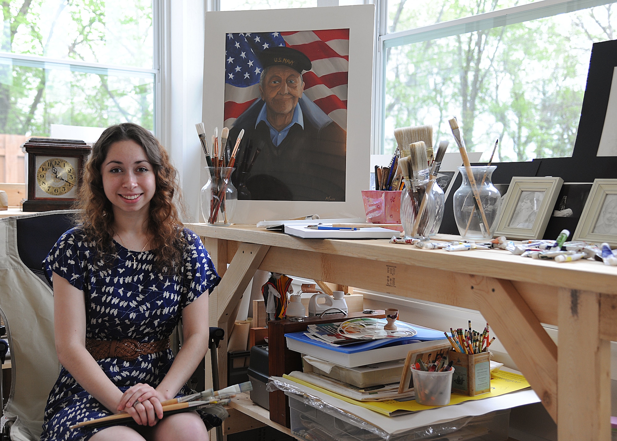 Natalie Michelle Mann sits next to her award-winning painting of WWII veteran Clarence Olson in her home studio on June 1, 2013, on Grand Forks Air Force Base, N.D. The idea to paint the veteran portrait came from an exchange between her and the subject, where he told Natalie about his war-time experience. (U.S. Air Force Photo/Airman 1st Class Zachiah Roberson)