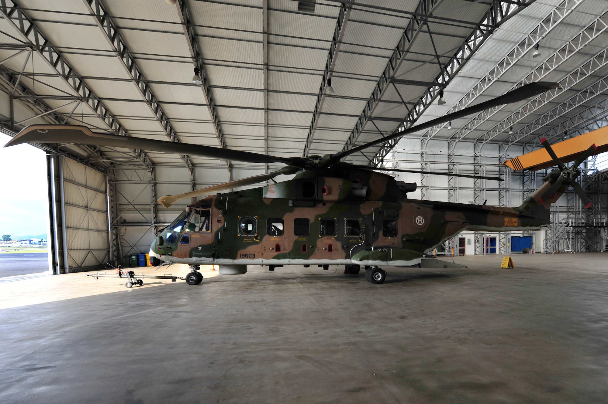 An EH-101 Merlin helicopter, ready for emergency and medical responses, in an aircraft hangar at Lajes Field, Azores.  The Portuguese Air Force utilizes this aircraft to conducts search and rescue missions as well as medical evacuations throughout the Azores islands.   Only two of the nine islands, Terceira and Sao Miguel, have major hospitals.   PoAF search and rescue missions transport people from other islands to the nearest hospital, often responding to women entering labor or people experiencing a health problem or a disabled vessel on the ocean.   (U.S. Air Force photo by Tech. Sgt. Chenzira Mallory/released)
