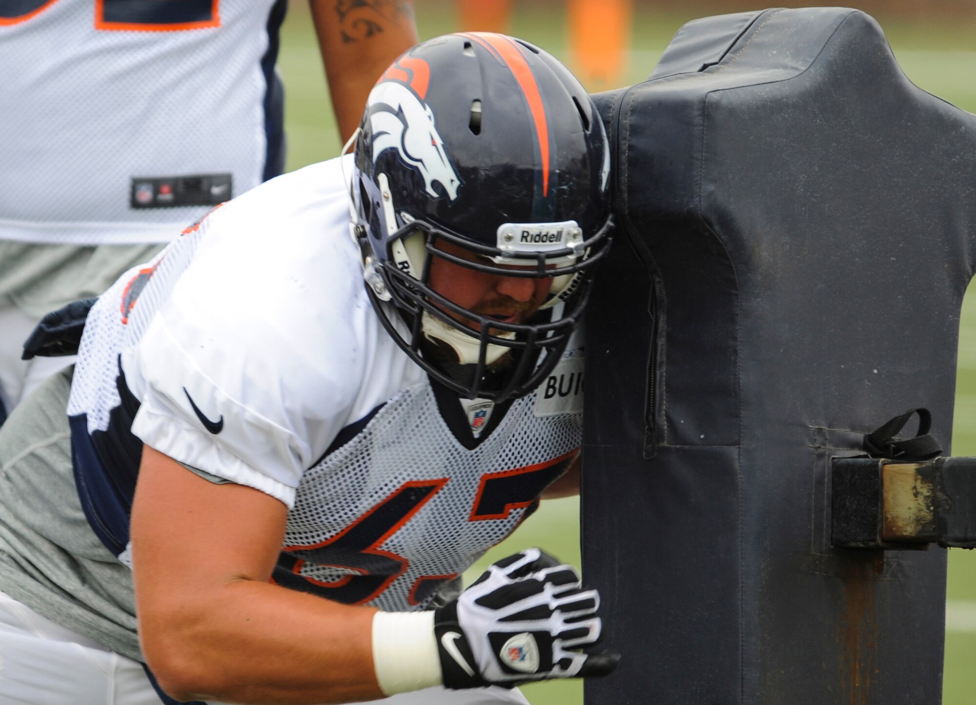 Benjamin Garland, Denver Broncos offensive guard, hits the sled during an offensive line drill at a Broncos training camp practice July 29, 2013, at the Broncos training facility, Englewood, Colo. Garland spent last season on the Broncos practice squad and transitioned from defensive tackle to offensive guard before the Broncos 2013 mini-camp. Garland is also a first lieutenant for the 140th Wing, Colorado Air National Guard, and served his annual commitment during the early part of 2013. (U.S. Air Force photo by Staff Sgt. Christopher Gross/Released)
