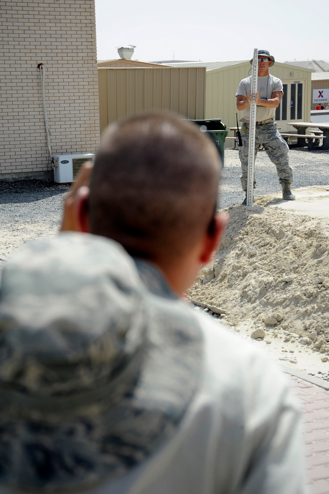 Senior Airman Adam Walden, 386th Expeditionary Civil Engineer Squadron, holds a Philadelphia Rod while Tech. Sgt. Mark Ondersma, 386th ECES, looks through an auto leveler here, July 29, 2013. Walden and Ondersma are both heavy equipment operators. They are taking measurements to ensure the base material is level all around the site before placement of a new building. Ondersma, a native of Hudsonville, Mich. is deployed out of the 110th Airlift Wing, Battle Creek, Mich., Air National Guard unit. Walden is also a member of the 110th A.W. and is a native of Clinton Mich. (U.S. Air Force photo by Master Sgt. Christopher A. Campbell)