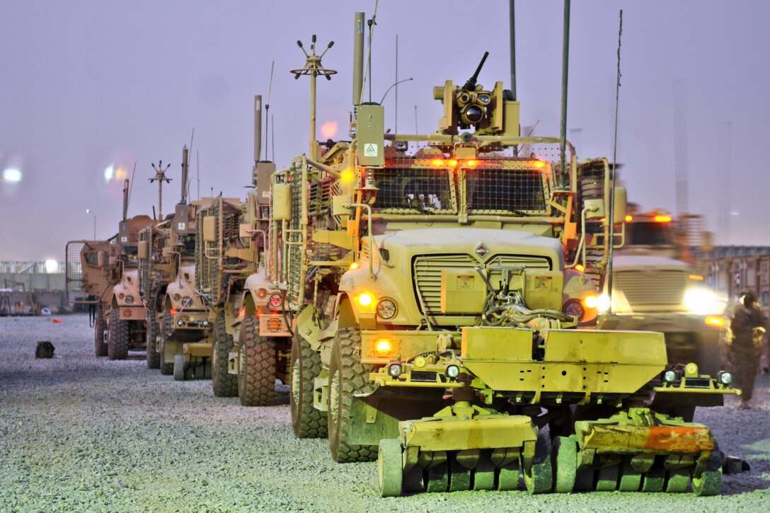 U.S. Army troops conduct safety checks and mount weapons on trucks before conducting convoy operations at night on Kandahar Airfield, Afghanistan, July 30, 2013.