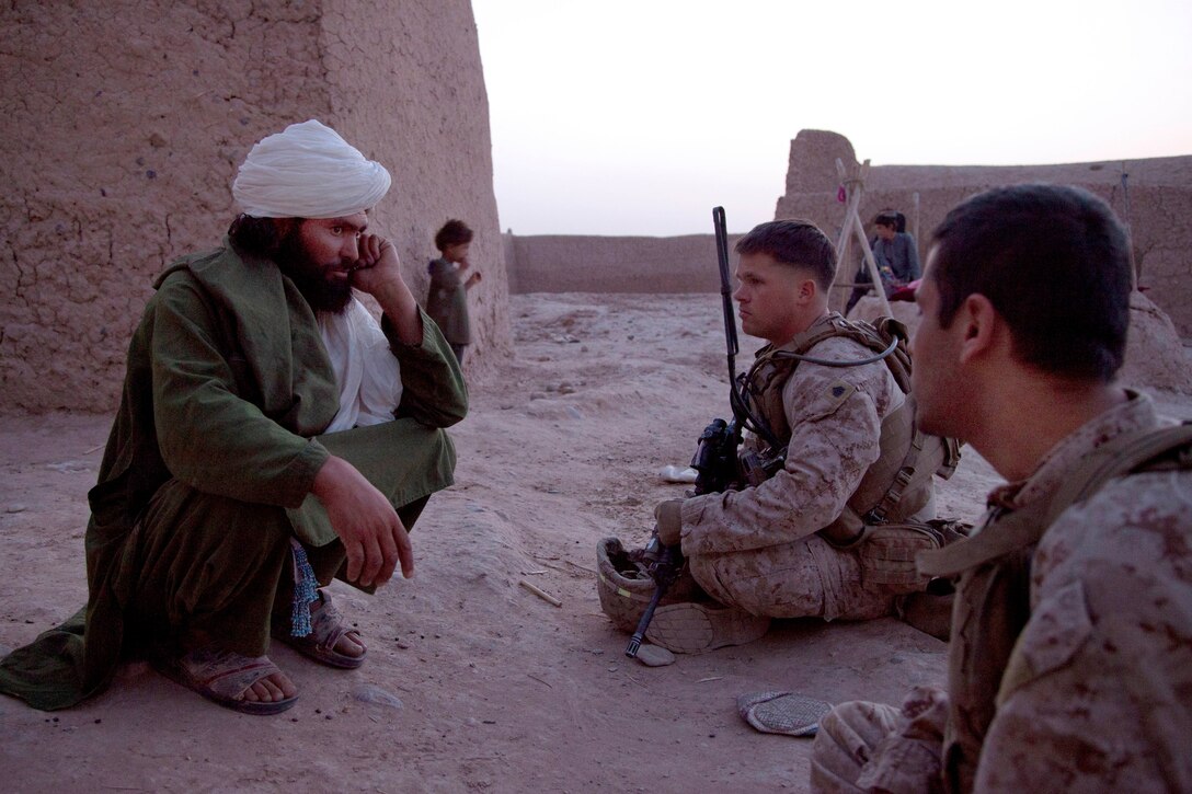 U.S. Marine Corps Sgt. Joshua Farrell, center, interviews an Afghan man during Operation Grizzly in Helmand province, Afghanistan, July 18, 2013. Farrell is assigned to Fox Company, 2nd Battalion, 2nd Marine Regiment.