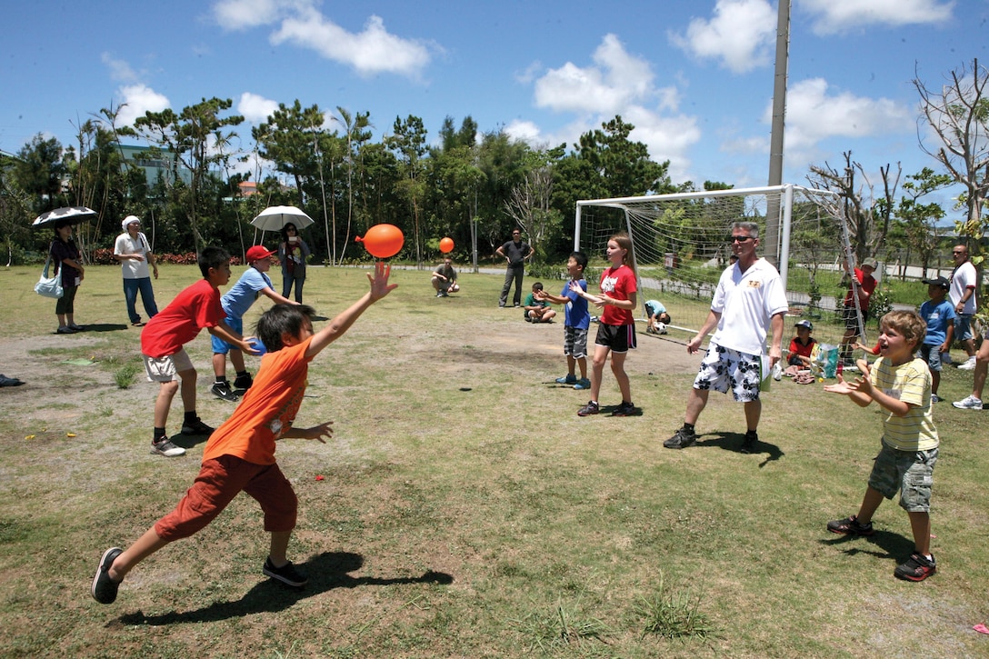 Japanese and American students participate in a water-balloon distance toss during the Kid Olympics July 27 at Camp Courtney. The Kid Olympics gave Japanese and American students the opportunity to partner with one another and share a day of fun. The event featured numerous sporting activities and opportunities for students from different cultures to connect. Photo by Lance Cpl. John S. Gargano