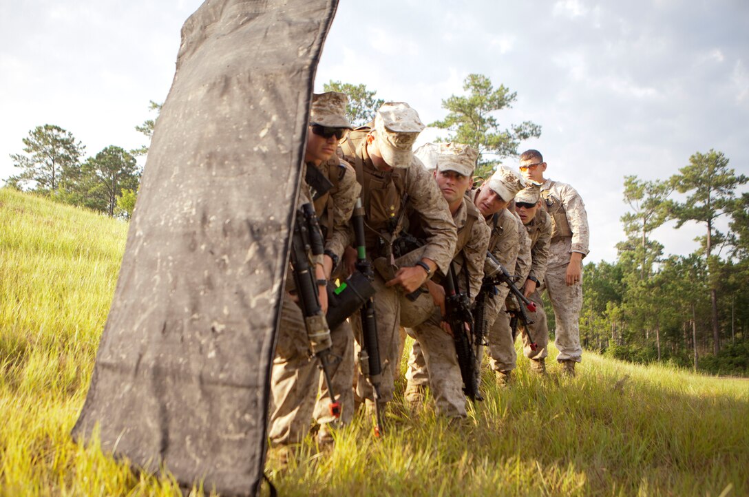 Marines with 2nd and 4th Combat Engineer Battalions and 8th Engineer Support Bn. practice stacking and holding the blast blanket prior to the urban demolition range here, July 24. The blast blanket protects the Marines from detonation, some as close as eight feet. Correct stack order and positioning is important because the pressure from the explosion can injure the Marines, especially at the end of the stack