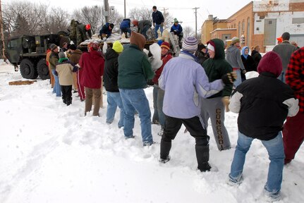 Residents of Moorhead, Minn., unload sandbags from the back of a Palletized Loading System truck from the Minnesota Army National Guard's E Company, 2nd Combined Arms Battalion, 136th Infantry regiment, and stack them in an area along the Red River, Thursday, March 26, 2009. Moorhead is expected to be hit with major flooding as the Red River continues to rise as a result of rain and snowmelt and is expected to crest at 41 feet by the end of the week. More than 250 Minnesota National Guard Soldiers and Airmen have been calle dup to state active duty to assist local authorities with traffic control, security as well as other tasks.