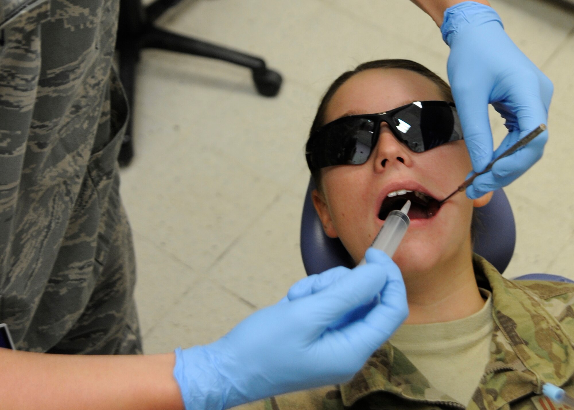 Senior Airman Zachary Mason uses a syringe to irrigate Airman 1st Class Danielle Adams’ gums during a follow-up appointment at the 379th Air Expeditionary Wing in Southwest Asia, July 26, 2013. Mason is a 379th Expeditionary Medical Operations Squadron dental assistant deployed from the U.S. Air Force Academy, Colo., and Adams is a 557th Expeditionary RED HORSE Squadron vehicle maintainer deployed from Malmstrom Air Force Base, Mont. (U.S. Air Force photo/Senior Airman Bahja J. Jones) 