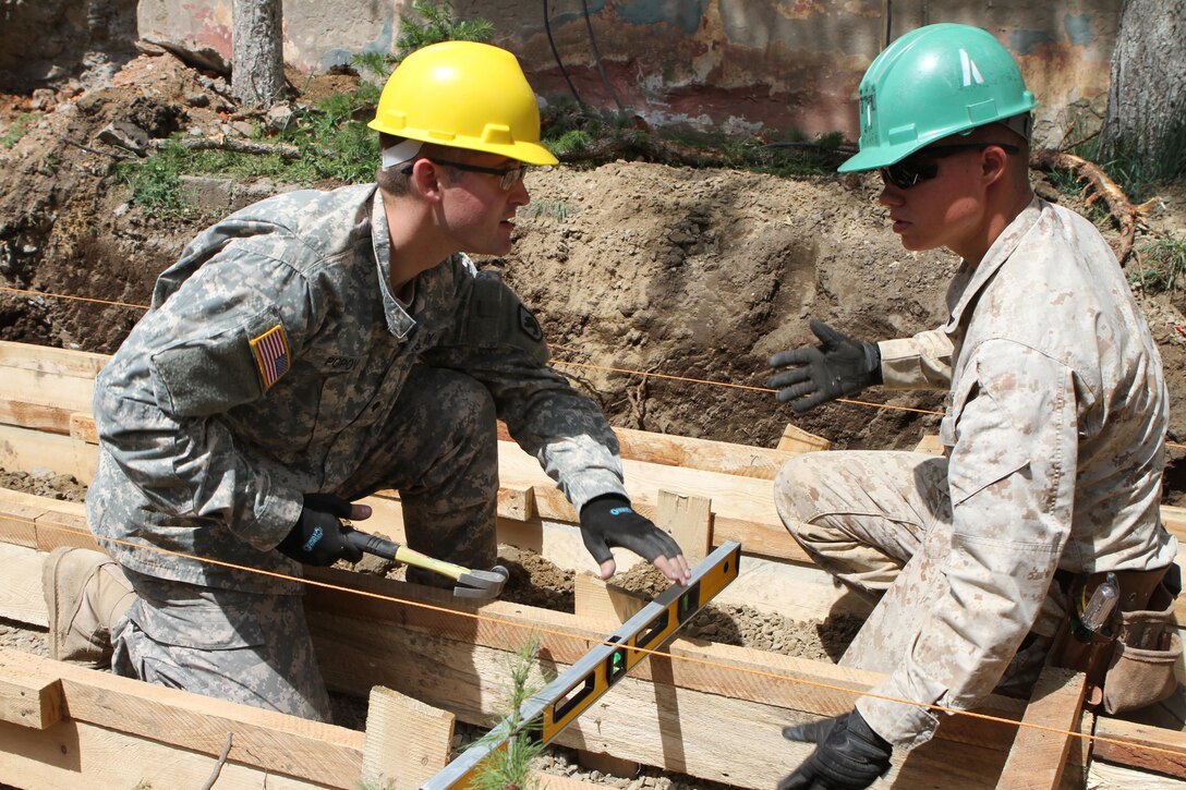 U.S. Army Specialist Aleksandr Popov with 176th Engineer Company (Vertical), 96th Troop Command, Washington Army National Guard, and U.S. Marine Lance Cpl. Bennett Russ with 9th Engineer Support Battalion, 3rd Marine Logistics Group, III Marine Expeditionary Force, check the level of a form before laying concrete during renovation work on Erdmiin Oyun school as part of Exercise Khaan Quest in the Nalaikh District of Ulaanbaatar, Mongolia, July 24. Khaan Quest is a regularly scheduled multinational exercise co-sponsored this year by U.S. Marine Corps Forces, Pacific, and hosted annually by the Mongolian Armed Forces, designed to promote regional peace and security. Popov is from Bonney Lake, Wash. Russ is from Winston-Salem, N.C.