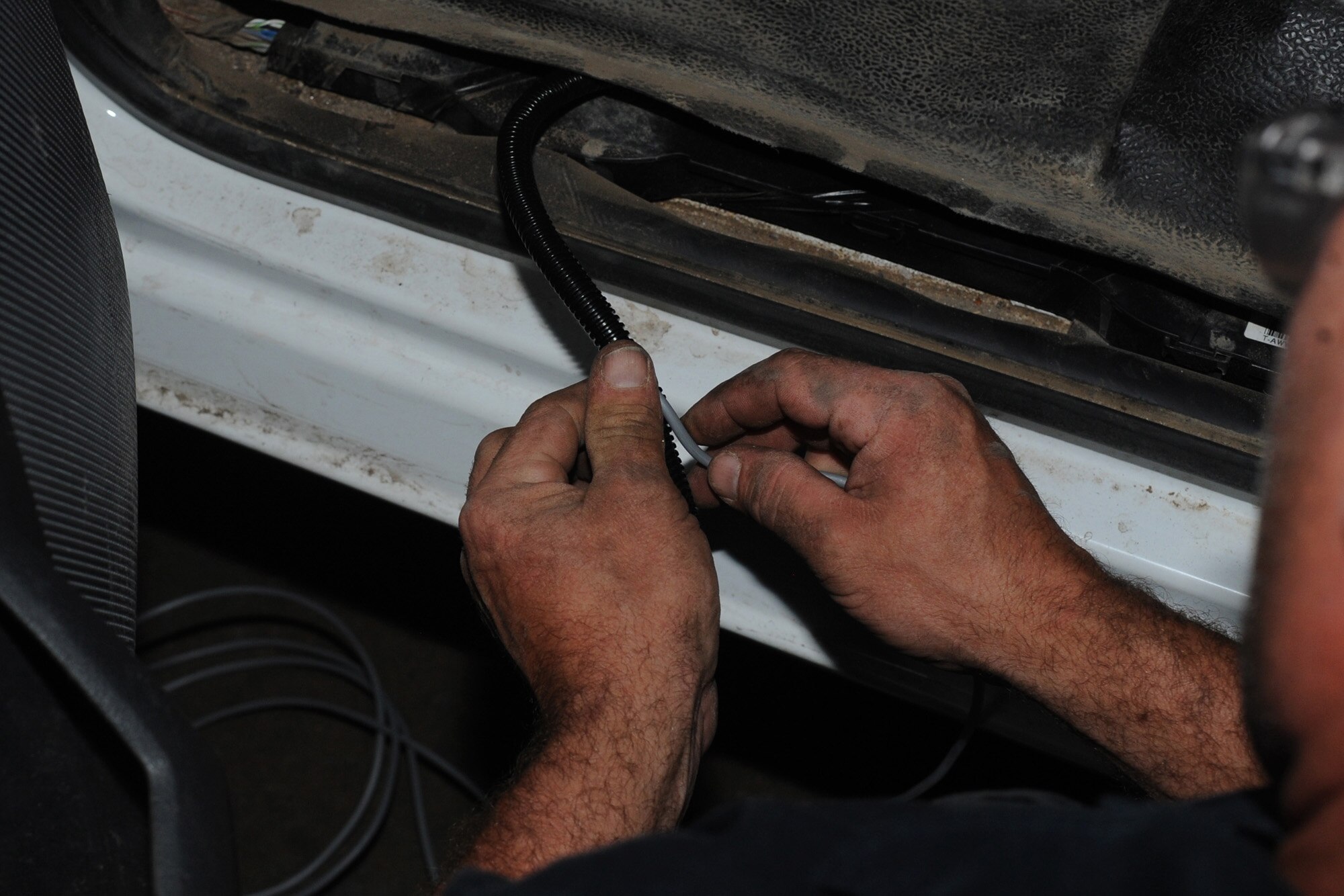 William Kent-Tadlock, 28th Logistics Readiness Squadron vehicle technician, feeds a wire through tubing while installing an automotive information module fuel management system at Ellsworth Air Force Base, S.D., July 23, 2013. All government vehicles have the system installed so its fuel system, engine diagnostics, odometer, idle time, and more can all be monitored wirelessly. (U.S. Air Force photo by Airman 1st Class Rebecca Imwalle/Released)