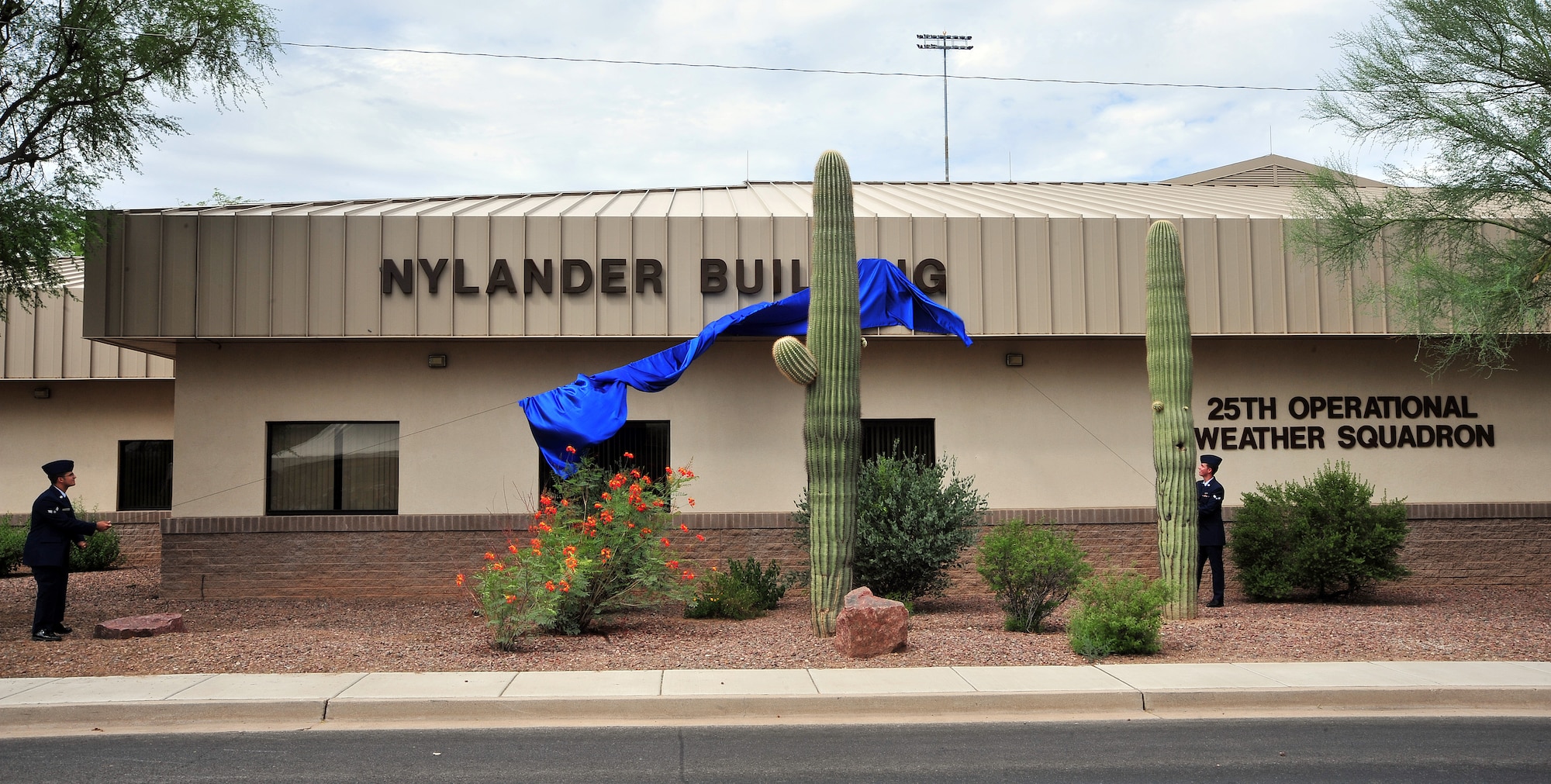 U.S. Air Force Airmen from the 25th Operational Weather Squadron unveil the 25th OWS as the Nylander Building at Davis-Monthan Air Force Base, Ariz., Aug. 1, 2013. Capt. Nathan Nylander died while deployed to Afghanistan in 2011 and was stationed at the 25th OWS prior to his deployment.(U.S. Air Force Photo by Airman 1st Class Josh Slavin/Released)