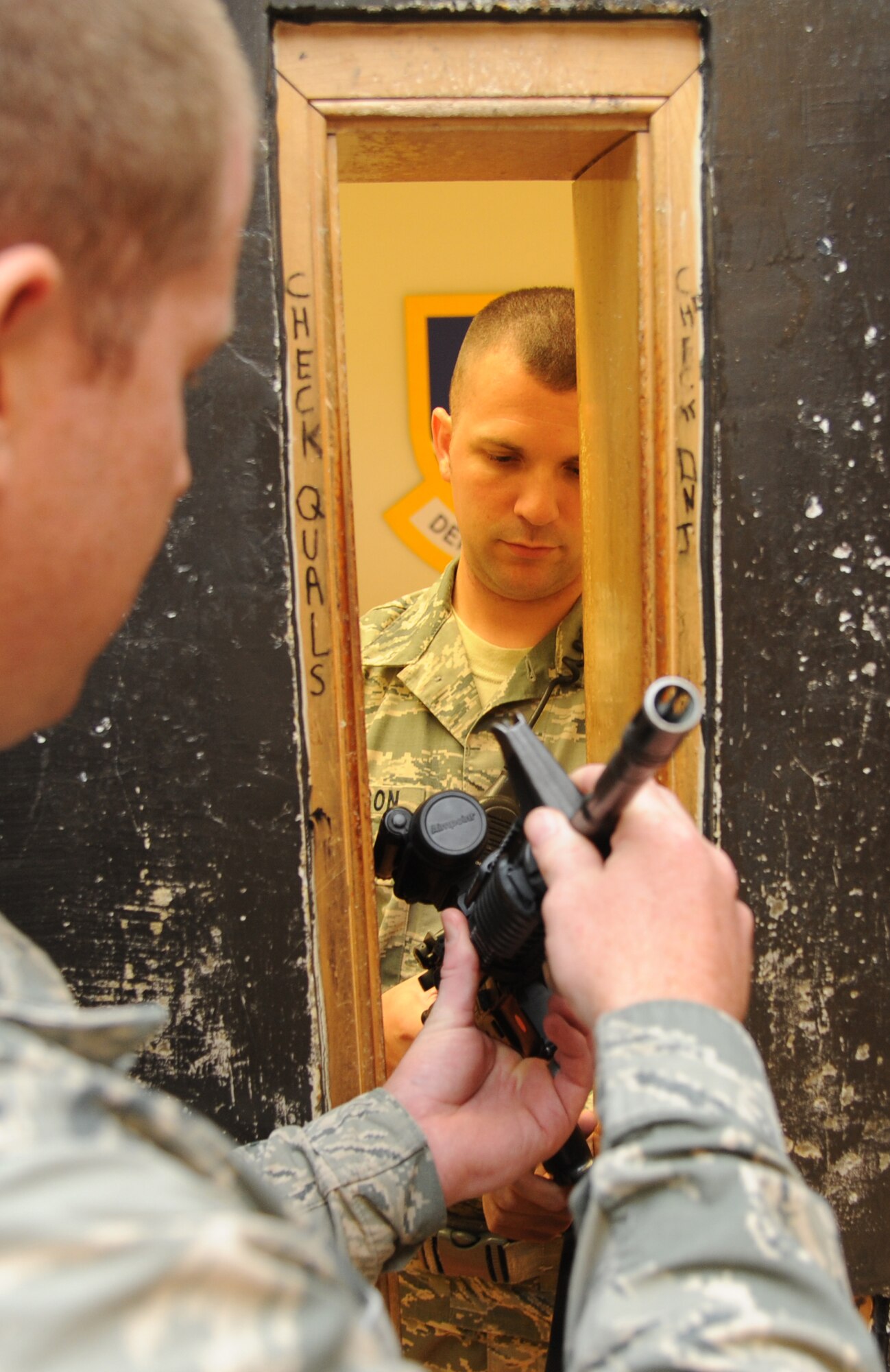 Staff Sgt. Michael O’Neil, 81st Security Forces Squadron armory NCO in charge, issues a weapon from inside the armory to Staff Sgt. Chris Pousson, 81st SFS, as they follow the safety steps of weapon issue and turn in procedures Aug. 2, 2013, at the 81st SFS building, Keesler Air Force Base, Miss.  The 81st SFS armory keeps weapons, ammunition, shared gear, and stores privately owned weapons for Keesler residents.  (U.S. Air Force photo by Kemberly Groue)