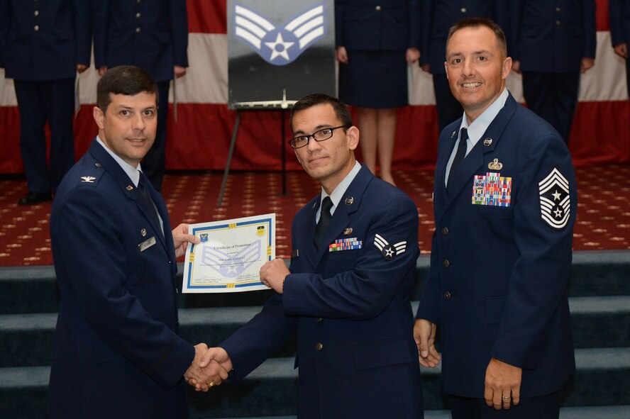 Senior Airman Michael Steele, from the 2nd Security Forces Squadron, receives a certificate of promotion from Col. Andrew Gebara, 2nd Bomb Wing commander, and Chief Master Sgt. Curtis Storms, 2nd BW command chief, during the July Wing Promotion Ceremony on Barksdale Air Force Base, La., July 31, 2013. (U.S. Air Force photo/Senior Airman Micaiah Anthony)