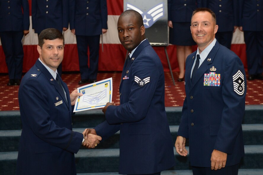 Senior Airman Willie Horton, from the 2nd Maintenance Squadron, receives a certificate of promotion from Col. Andrew Gebara, 2nd Bomb Wing commander, and Chief Master Sgt. Curtis Storms, 2nd BW command chief, during the July Wing Promotion Ceremony on Barksdale Air Force Base, La., July 31, 2013. (U.S. Air Force photo/Senior Airman Micaiah Anthony)