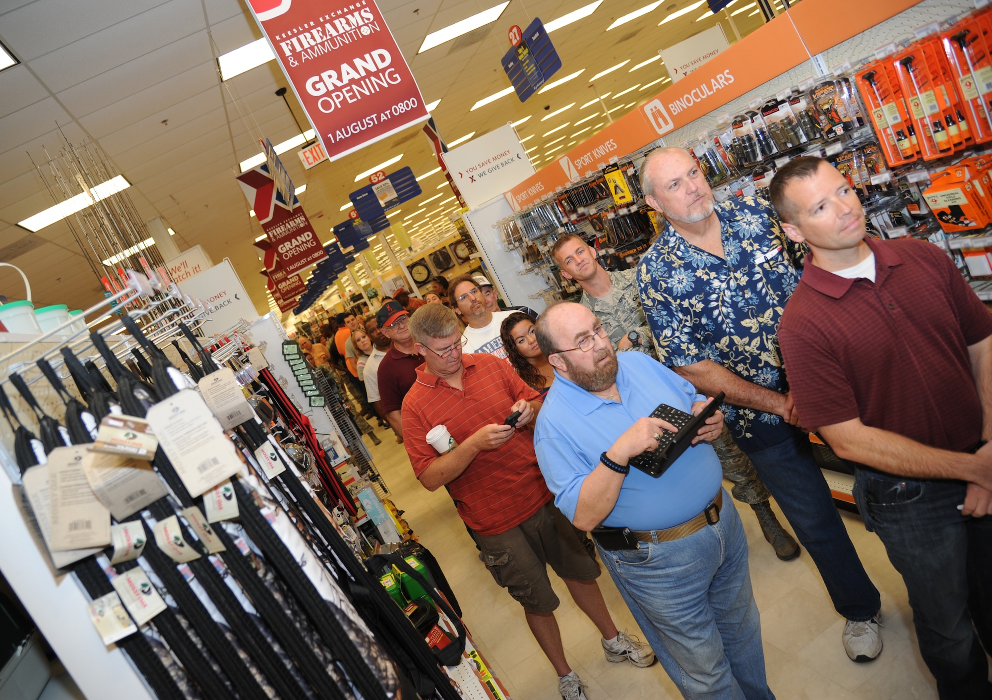 Keesler personnel and retirees stand in line for the firearms and ammunition section grand opening at the base exchange Aug. 1, 2013, at Keesler Air Force Base, Miss.  Acquiring a weapon at the exchange is proceeded by several commander-approved safety measures, and is followed by one of three required actions by the customer to keep the base safe and secure.  (U.S. Air Force photo by Kemberly Groue)