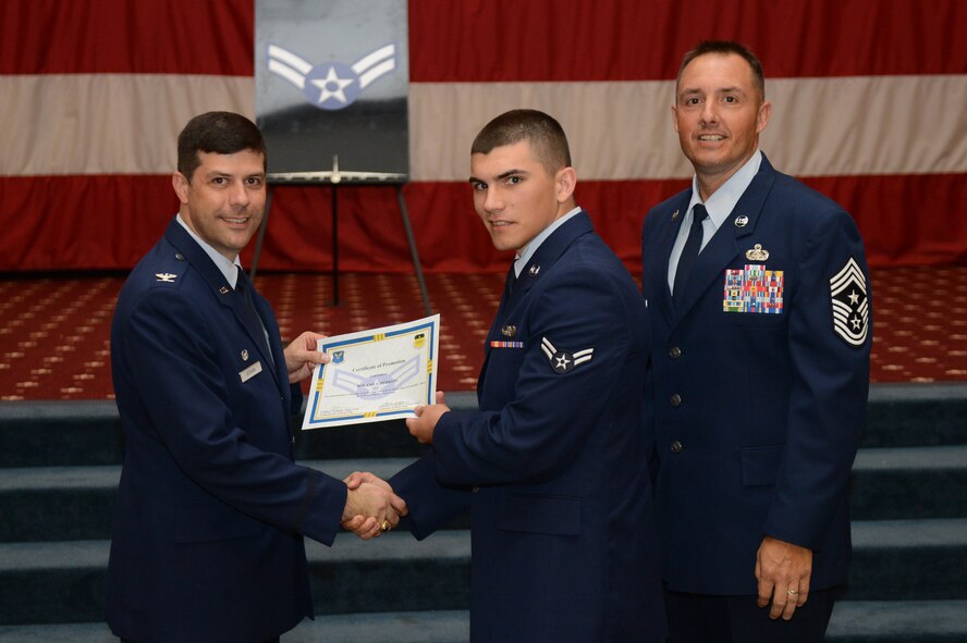 Airman 1st Class Roland Perkins, from the 2nd Communication Squadron, receives a certificate of promotion from Col. Andrew Gebara, 2nd Bomb Wing commander, and Chief Master Sgt. Curtis Storms, 2nd BW command chief, during the July Wing Promotion Ceremony on Barksdale Air Force Base, La., July 31, 2013. (U.S. Air Force photo/Senior Airman Micaiah Anthony)