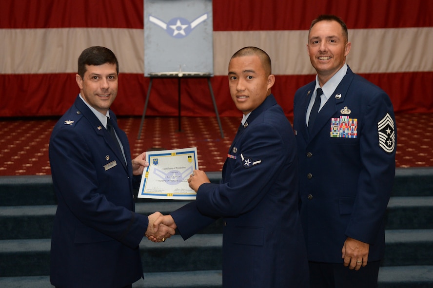 Airman Khoi Pham, from the 2nd Civil Engineer Squadron, receives a certificate of promotion from Col. Andrew Gebara, 2nd Bomb Wing commander, and Chief Master Sgt. Curtis Storms, 2nd BW command chief, during the July Wing Promotion Ceremony on Barksdale Air Force Base, La., July 31, 2013. (U.S. Air Force photo/Senior Airman Micaiah Anthony)
