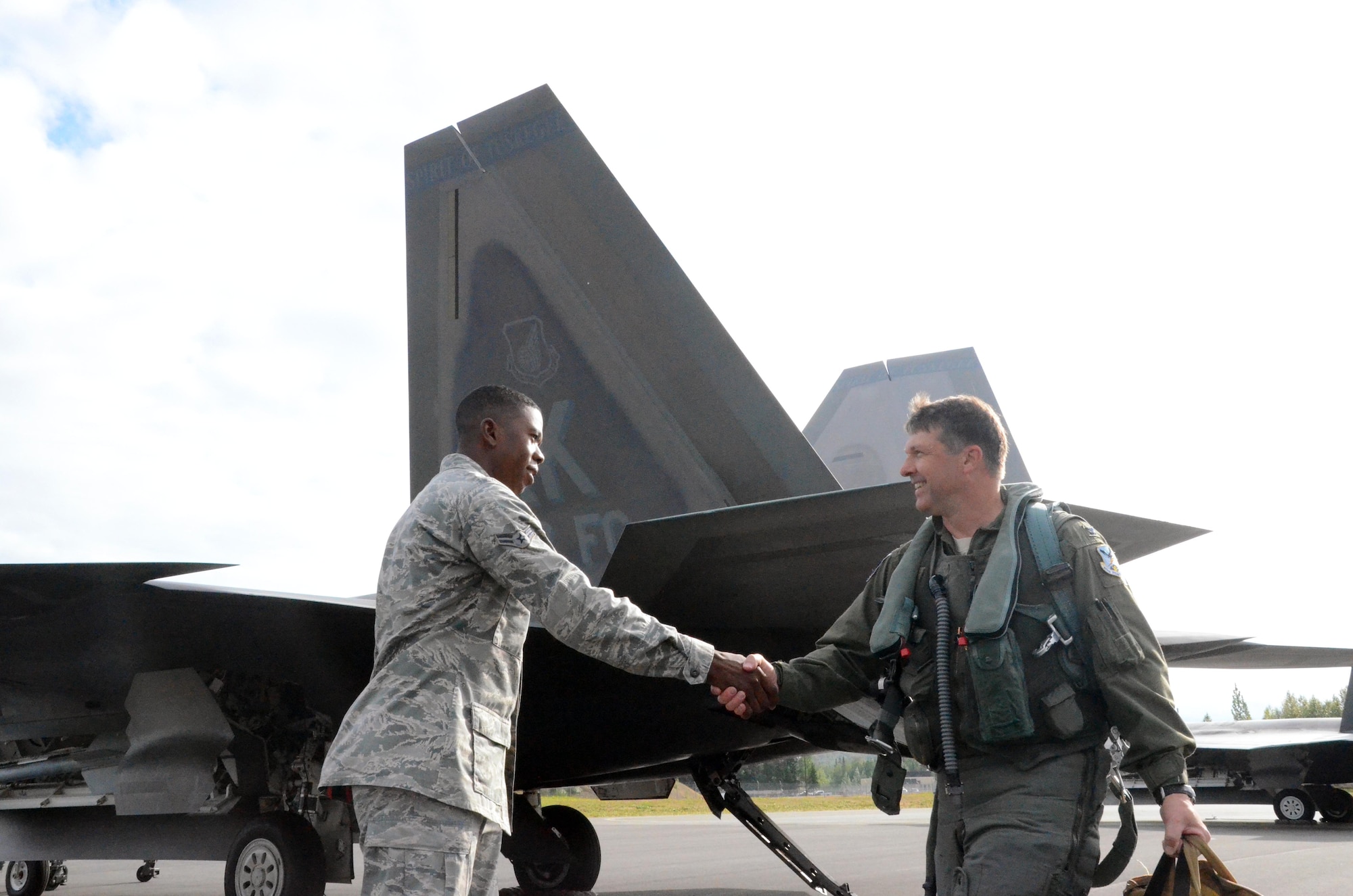 Airman 1st Class Jermaine James, 477th Aircraft Maintenance Squadron F-22 crew chief, greets Col. Tyler Otten, 477th Fighter Group commander before his flight here July 31. This was the first time tail number 147 has flown after being transformed into the 477th Fighter Group flagship.  The words “Spirit of Tuskegee” painted across the tail, a nod to the units Tuskegee Airmen heritage.  The Reserve 477th Fighter Group was previously the 477th Bombardment Group, a Tuskegee unit activated in 1944. The group's 302nd Fighter Squadron historically was part of the 332nd Fighter Group, also known as "The Redtails" the famous all-black unit that fought both American prejudice and the axis powers in Europe.  (U.S. Air Force/ Tech. Sgt. Andy Eichorst)