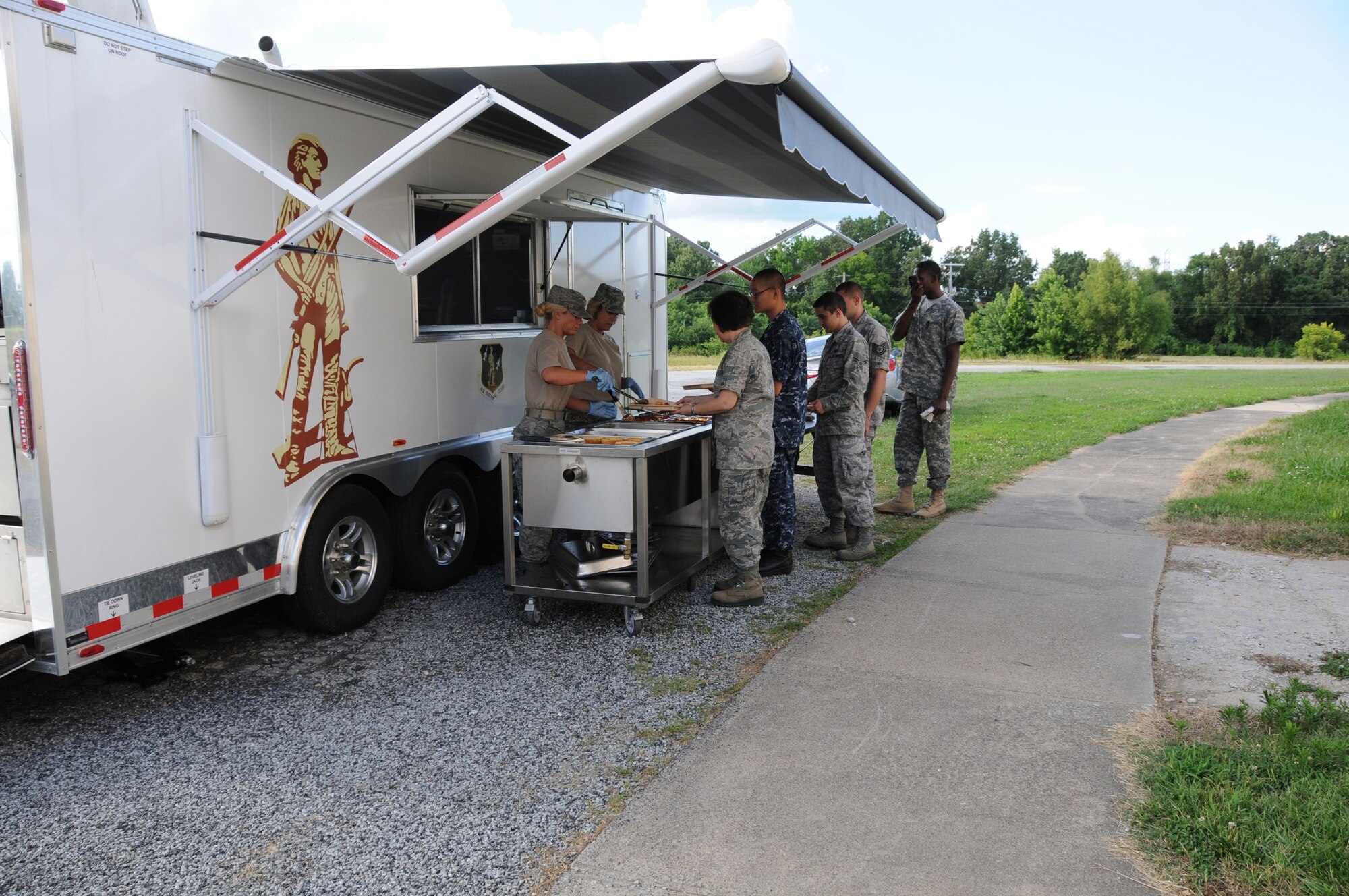 U.S. Air Force Tech. Sgt. Donna Hooper (left) and Master Sgt. Krista Lindsey, Force Support Flight, 123d Airlift Wing, Louisville, Kentucky, serve lasagna in front of a Disaster Response Mobile Kitchen Trailer (DRMKT) July 15 at ‘Hope of Martin’ Innovative Readiness Training held at Martin Middle School in Martin, Tenn. (U.S. Air National Guard photo by Master Sgt. Carlos J. Claudio/Released).