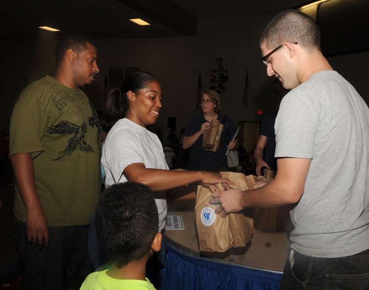 Senior Airman Kimberly Smith, 2nd Logistics Readiness Squadron, receives school supplies from Airman 1st Class Bryan Pyszk, Back-to-School volunteer, on Barksdale Air Force Base, La., July 29, 2013. The Back-to-School event was held to provide families the opportunity to meet and talk to their children's prospective principals and faculty regarding issues that would otherwise not be addressed until the very start of the school semester. (U.S. Air Force photo/Senior Airman Kristin High)