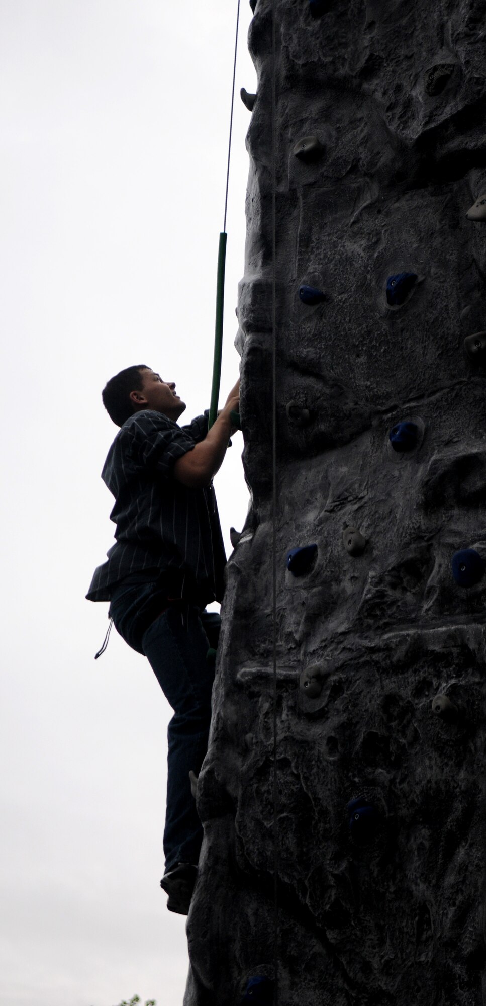 U.S. Air Force Airman 1st Class Matthew Holznagel, 352nd Special Operations Group crew chief from Medical Lake, Wash., climbs a rock wall at the Unaccompanied Airmen Appreciation Day Aug. 2, 2013, on RAF Mildenhall. Despite early thunderstorms, hundreds of Airmen were able to relax and hang out with friends. Entertainment included a live band, DJ, a dodgeball tournament and inflatable obstacles. (U.S. Air Force photo by Staff Sgt. Austin M. May/Released)