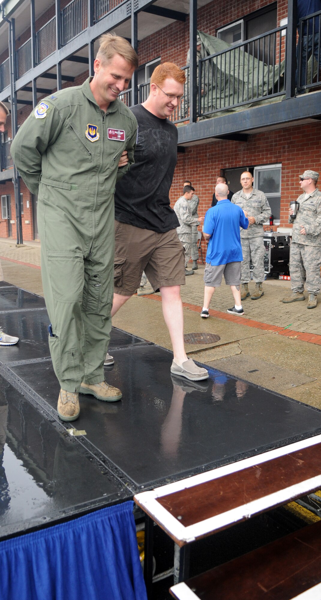 U.S. Air Force Col. David Cox, 100th Air Refueling Wing vice commander, is led offstage in handcuffs by U.S. Air Force Staff Sgt. Jonathan Williams, 100th Security Forces Squadron trainer from Visalia, Calif., during a mock arrest at the Unaccompanied Airmen Appreciation Day Aug. 2, 2013, on RAF Mildenhall. Before the event, coworkers arranged to have each other arrested and jailed on humorous charges. The Unaccompanied Airmen Appreciation Day allowed Airmen serving at RAF Mildenhall without families to enjoy a day of leisure activities orchestrated specifically for them as a show of appreciation for their unique circumstances. (U.S. Air Force photo by Staff Sgt. Austin M. May/Released)