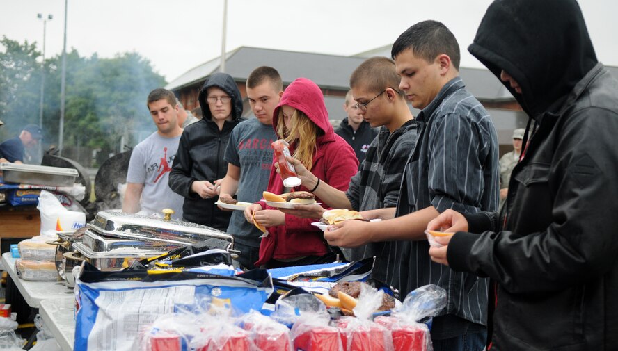 U.S. Air Force Airmen line up for hamburgers and hot dogs at the Unaccompanied Airmen Appreciation Day Aug. 2, 2013, on RAF Mildenhall, England. The RAF Mildenhall Chiefs' Group cooked and served food while Airmen enjoyed entertainment including live music, a DJ, inflatable obstacles and a rock-climbing wall. The event allowed Airmen serving at RAF Mildenhall without families to enjoy a day of leisure activities orchestrated specifically for them as a show of appreciation for their unique circumstances. (U.S. Air Force photo by Staff Sgt. Austin M. May/Released)