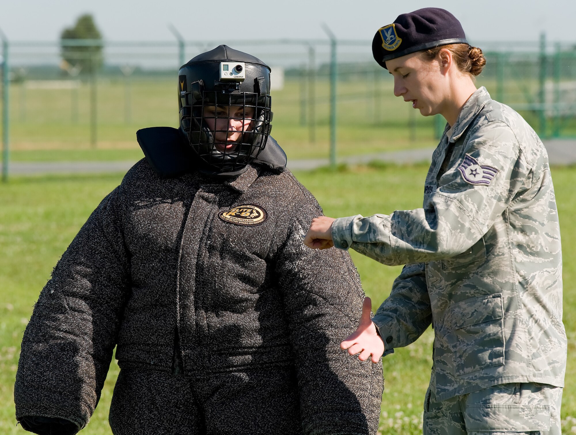 Staff Sgt. Christine Campos, right, a military working dog trainer with the 436th Security Forces Squadron, instructs  Ashley Barnas, a reporter with The News Journal, Wilmington, Del., on how a MWD will attack her arm July 30, 2013, at Dover Air Force Base, Del. Barnas donned a complete ?bite suit? and volunteered to be pursued by a MWD. (U.S. Air Force photo/Roland Balik)