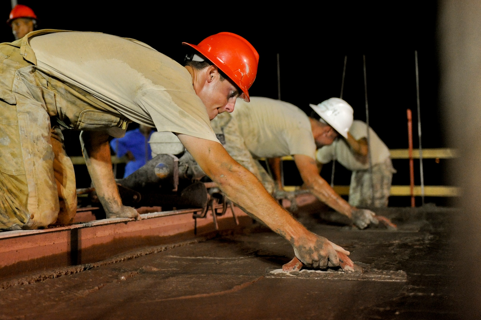 U.S. Air Force Senior Airman Andrew Tucker, 557th Expeditionary RED HORSE Squadron pavement and construction apprentice, Uses a magnesium float to level out freshly laid concrete to the second floor of a building at an undisclosed location in Southwest Asia Aug. 1, 2013. The concrete is leveled and smoothed out shortly after being poured, ensuring no dips or bulges are present when it dries. Tucker is native to Tullahoma, Tenn., and is deployed from Malmstrom Air Force Base, Mont. (U.S. Air Force photo by Staff Sgt. Joshua J. Garcia)