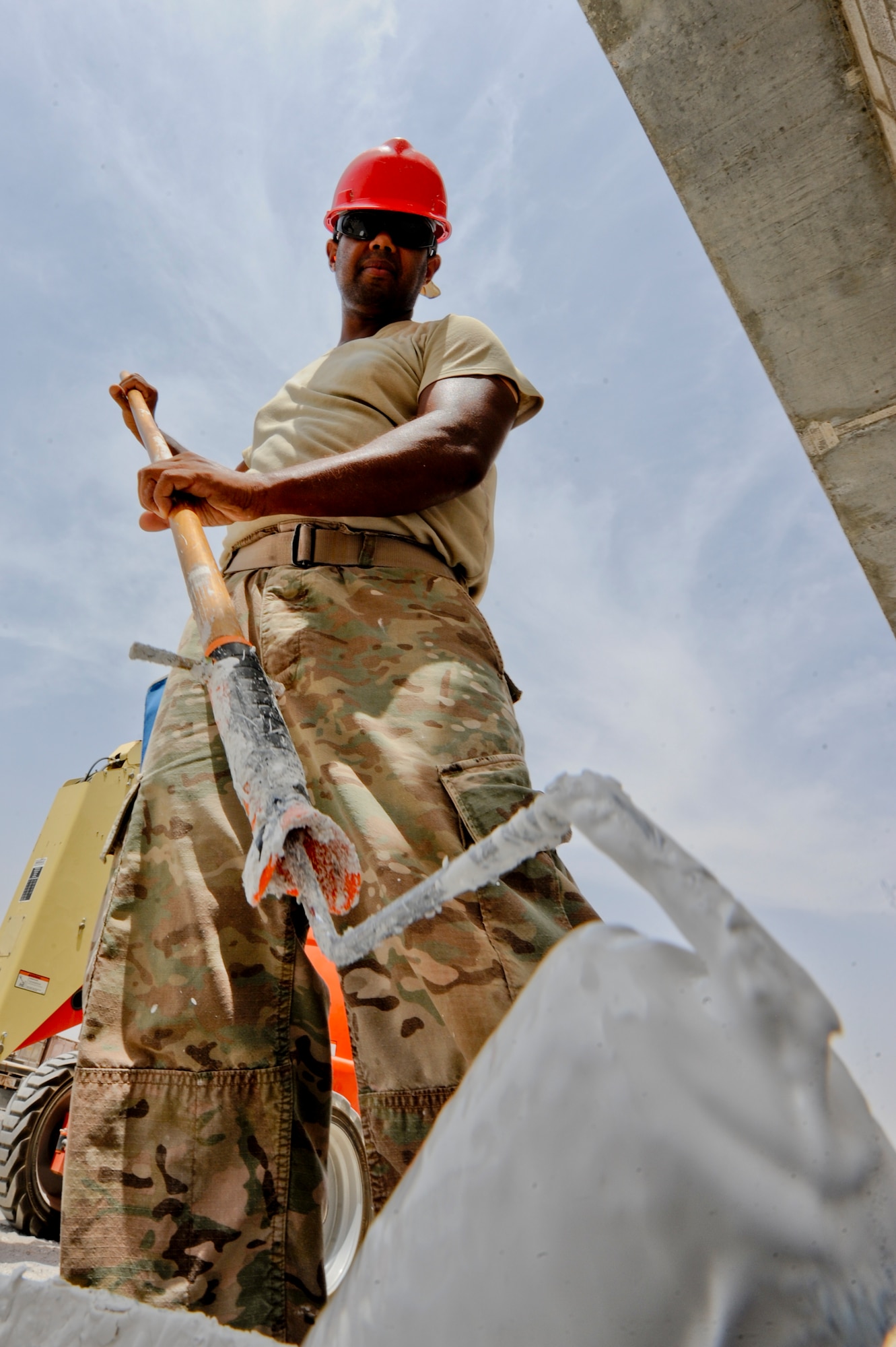 U.S. Air Force Staff Sgt. Duane Bacchus, 557th Expeditionary RED HORSE Squadron structures journeyman, prepares to paint the exterior wall of a building at an undisclosed location in Southwest Asia July 31, 2013. The paint is being applied to a brand-new work facility for the RED HORSE squadron. Bacchus is native to Houston, Texas and is deployed from Malmstrom Air Force Base, Mont. (U.S. Air Force photo by Staff Sgt. Joshua J. Garcia) 