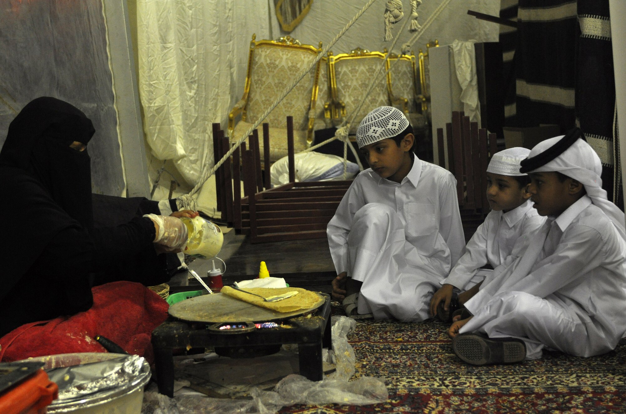 Young boys watch as a local woman makes roqaq bread with eggs and cheese during a Ramadan tent celebration hosted by local government officials near the 379th Air expeditionary Wing in Southwest Asia, July 24, 2013. The tent celebration is a late evening gathering with light snacks that follows the breaking of the fast dinner during the Muslim holy month of Ramadan. (U.S. Air Force photo/1st Lt. Susan Harrington) 