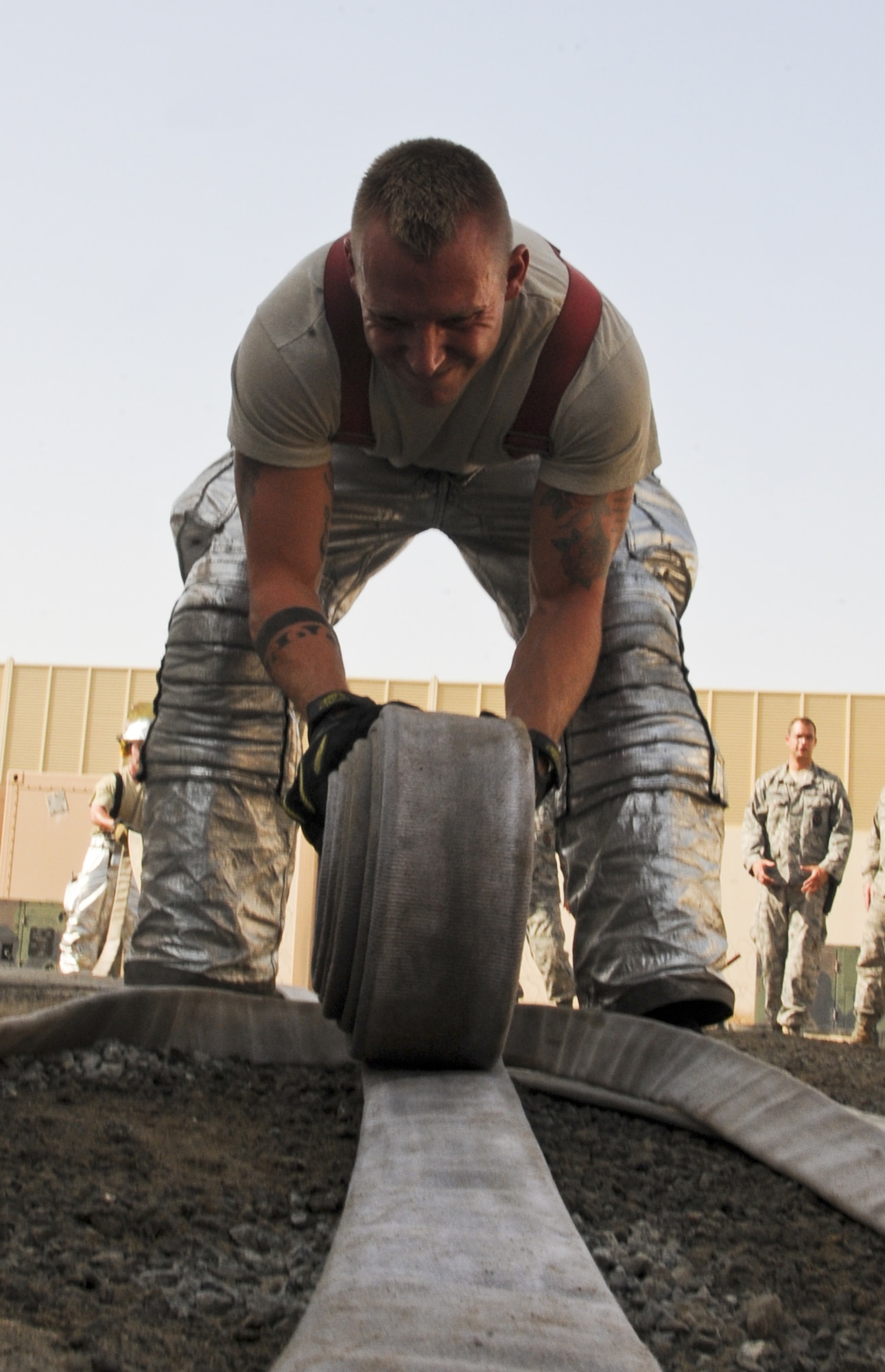 U.S. Air Force Staff Sgt. Bryan Buck, 380th Civil Engineer Squadron Fire Department crew chief, rolls up a hose after an exercise at an undisclosed location in Southwest Asia Aug. 1, 2013. . During the exercise, Bucks’ team was required to show the capability to swiftly deploy handline hoses. Buck calls Milton, Penn., home and is deployed from Mountain Home Air Force Base, Idaho. (U.S. Air Force photo by Staff Sgt. Jacob Morgan)