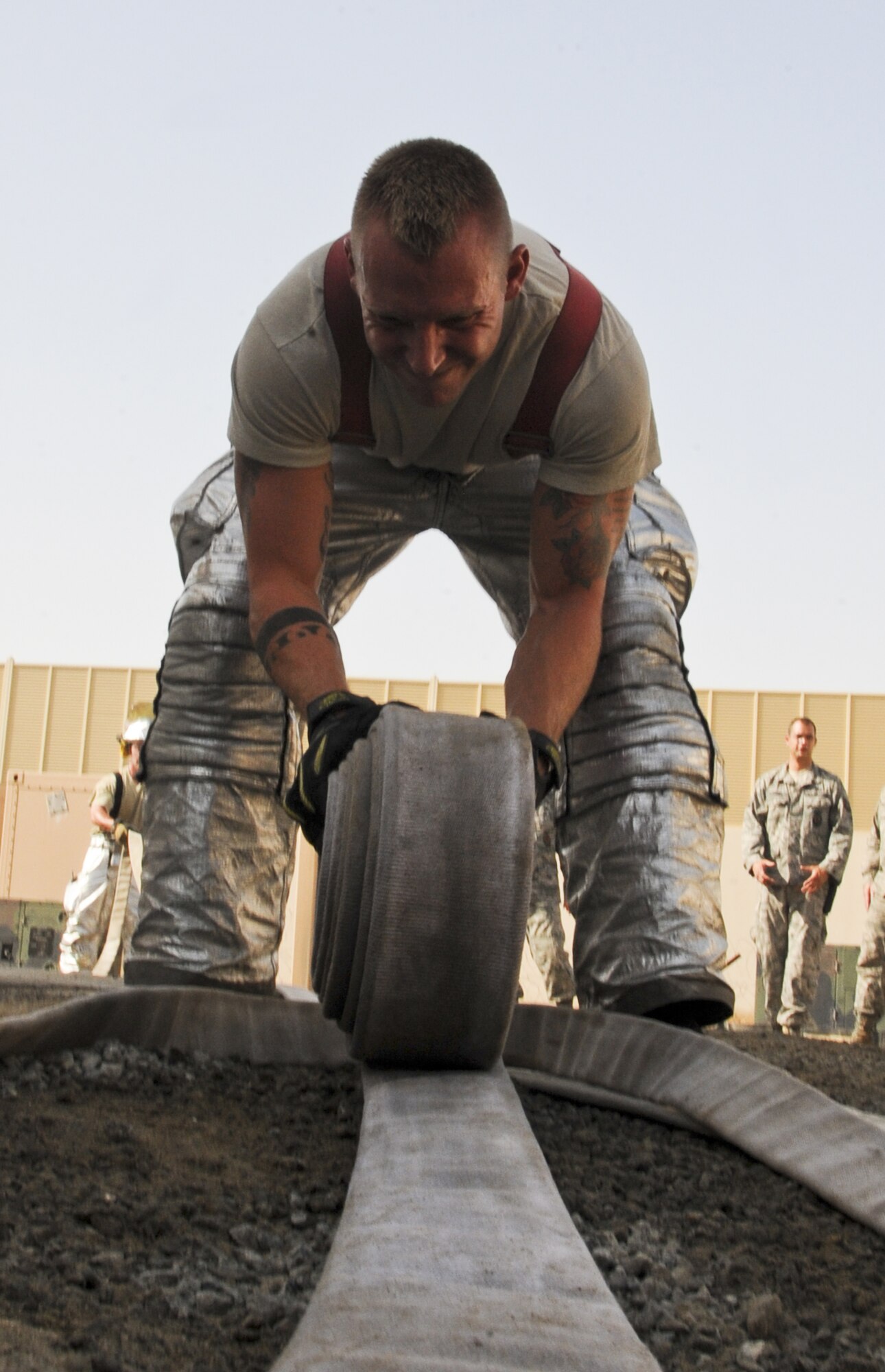 U.S. Air Force Staff Sgt. Bryan Buck, 380th Civil Engineer Squadron Fire Department crew chief, rolls up a hose after an exercise at an undisclosed location in Southwest Asia Aug. 1, 2013. . During the exercise, Bucks’ team was required to show the capability to swiftly deploy handline hoses. Buck calls Milton, Penn., home and is deployed from Mountain Home Air Force Base, Idaho. (U.S. Air Force photo by Staff Sgt. Jacob Morgan)