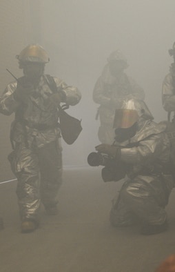 U.S. Air Force Staff Sgt. Nathan Cinq-Mars, left, 380th Civil Engineer Squadron Fire Department crew chief, uses a radio to communicate with a team outside while U.S. Air Force Airman 1st Class Andre Adams, 380th Civil Engineer Squadron Fire Department handlineman, prepares to spray an exercise fire at an undisclosed location in Southwest Asia Aug. 1, 2013. Firefighters are often faced with being able to make decisions on the spot in the face of danger. Cinq-Mars calls Seekonk, Mass., home and is deployed from Joint Base Langley-Eustis. Adams calls San Antonio, Texas, home and is deployed from Holloman Air Force Base, N.M. (U.S. Air Force photo by Staff Sgt. Jacob Morgan)