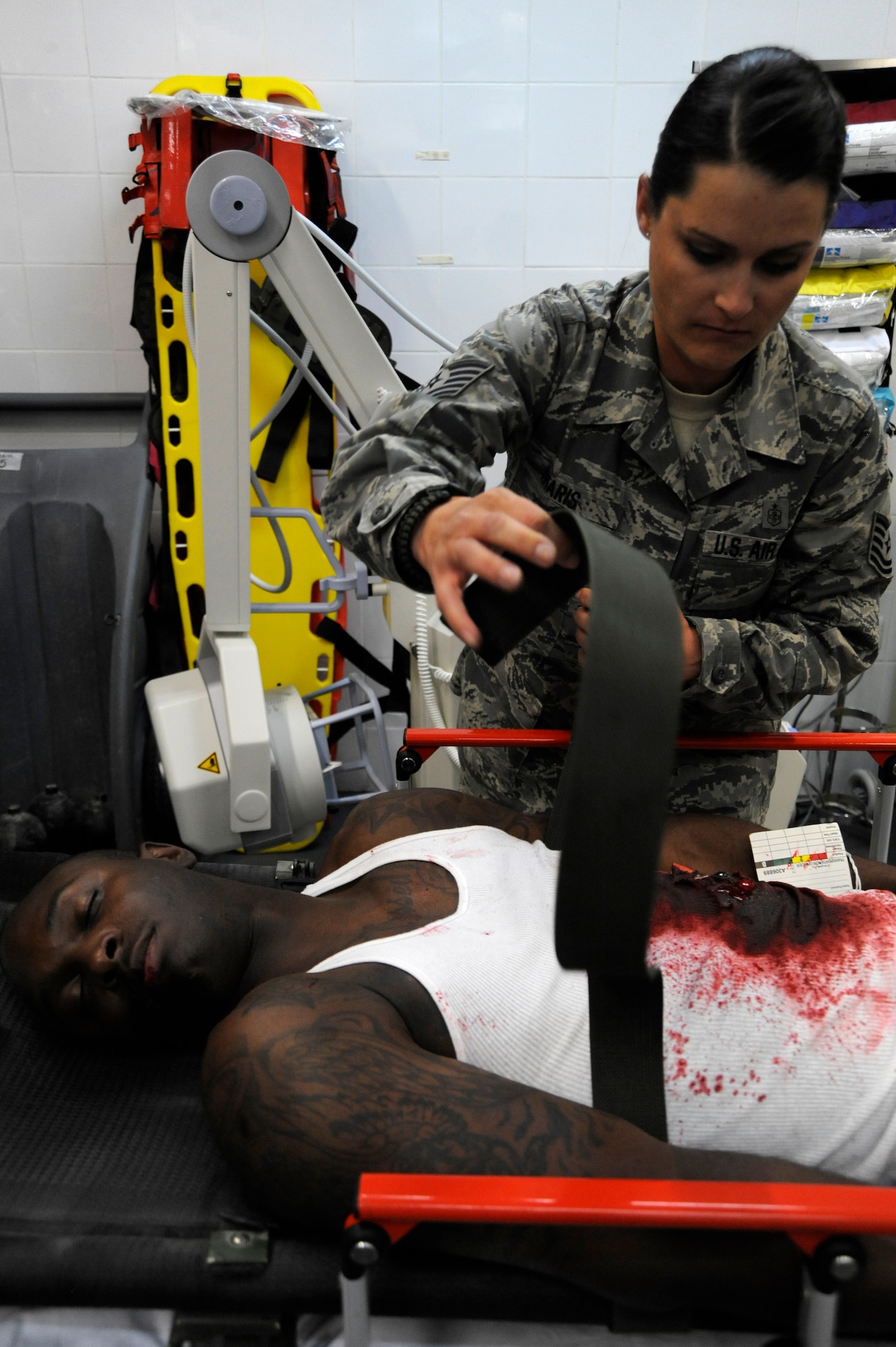 Tech. Sgt. Miranda Pharis carefully unstraps Senior Airman Ricky Smith from a litter during a 379th Expeditionary Medical Group mass casualty exercise at the 379th Air Expeditionary Wing in Southwest Asia, July 26, 2013. All participating Airmen acting as casualties had moulages applied to make the injuries look as real as possible. Pharis is a 379th Expeditionary Medical Support Squadron health service manager and Smith is a 379th Expeditionary Medical Support Squadron medical logistics technician. Both are deployed from Joint Base Langley-Eustis, Va. (U.S. Air Force photo/Senior Airman Bahja J. Jones) 