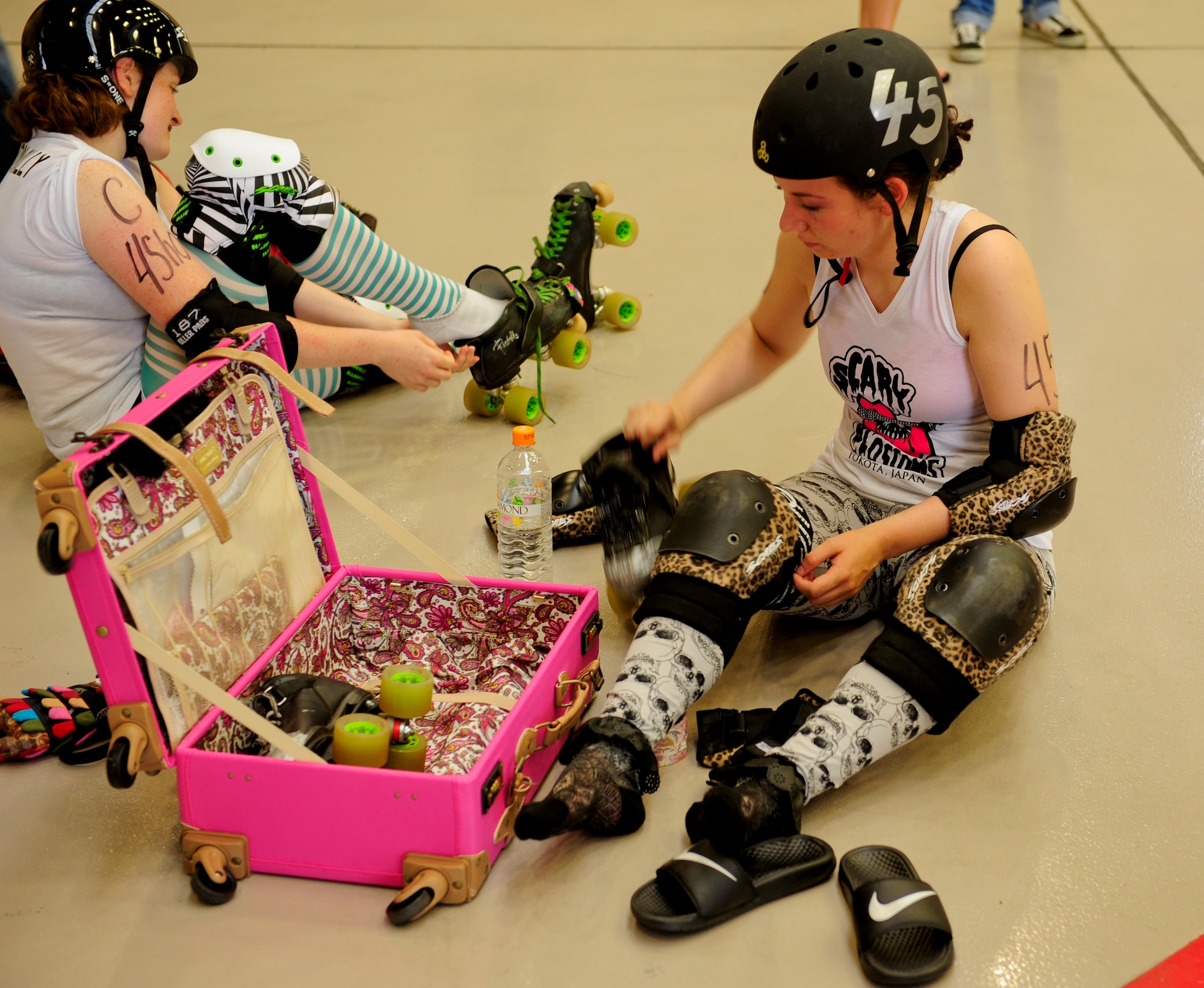 (Front) Senior Airman Josephine Grenier, 374th Security Forces Squadron, and Staff Sgt. Corinne Lamoree, 374th Operational Support Squadron, put on their equipment before their inner-team bout inside Hangar 15 at Yokota Air Base, Japan, July 27, 2013. The Scary Blossom members were split into two teams during their bout: the Skeletons and the Reapers. (U.S. Air Force photo by Senior Airman Michael Washburn)