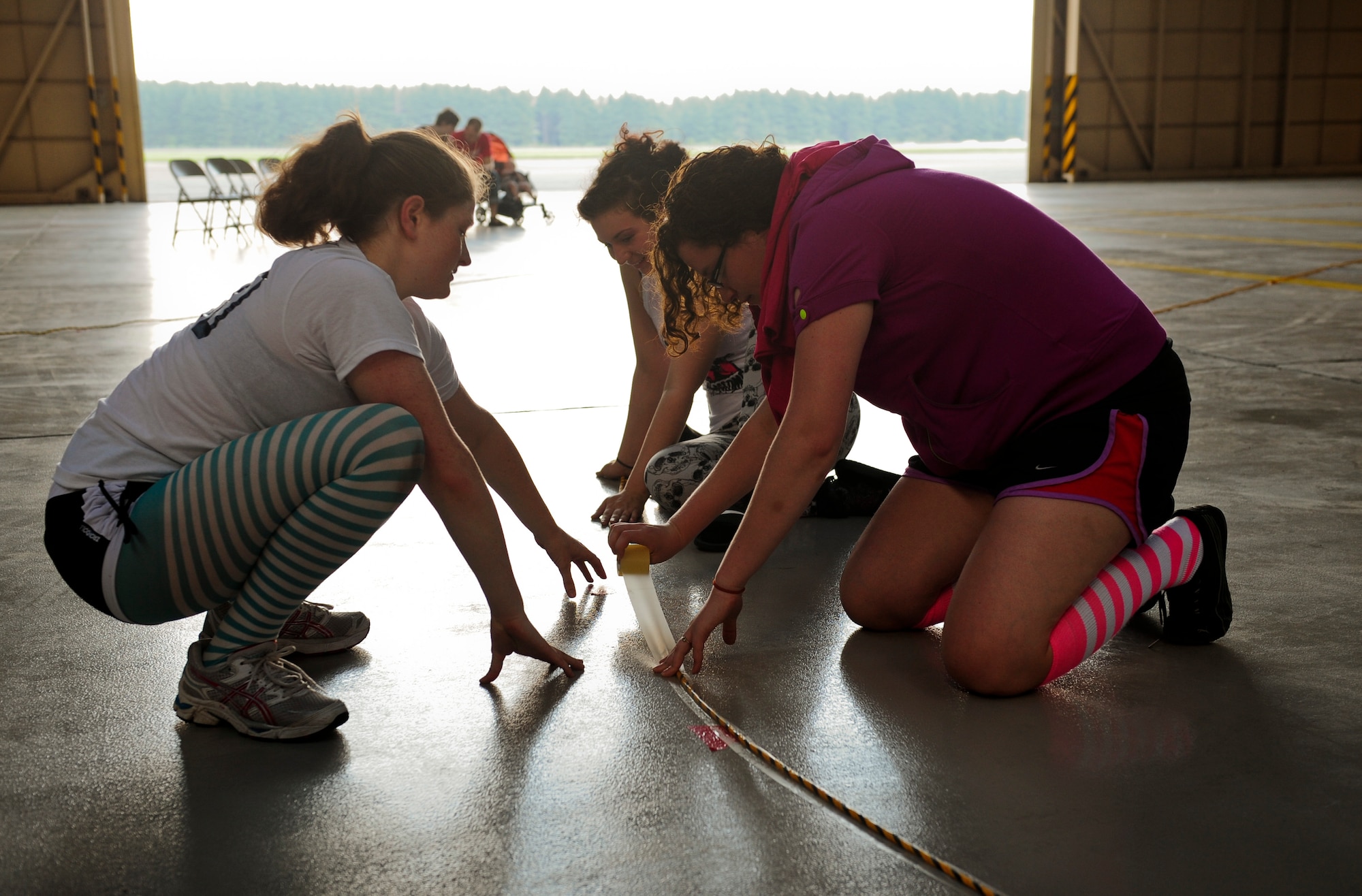 Members of the Scary Blossoms roller derby team, along with volunteer Ally Mis, help set up the track before their inner-team bout inside Hangar 15 at Yokota Air Base, Japan, July 27, 2013. (U.S. Air Force photo by Senior Airman Michael Washburn)