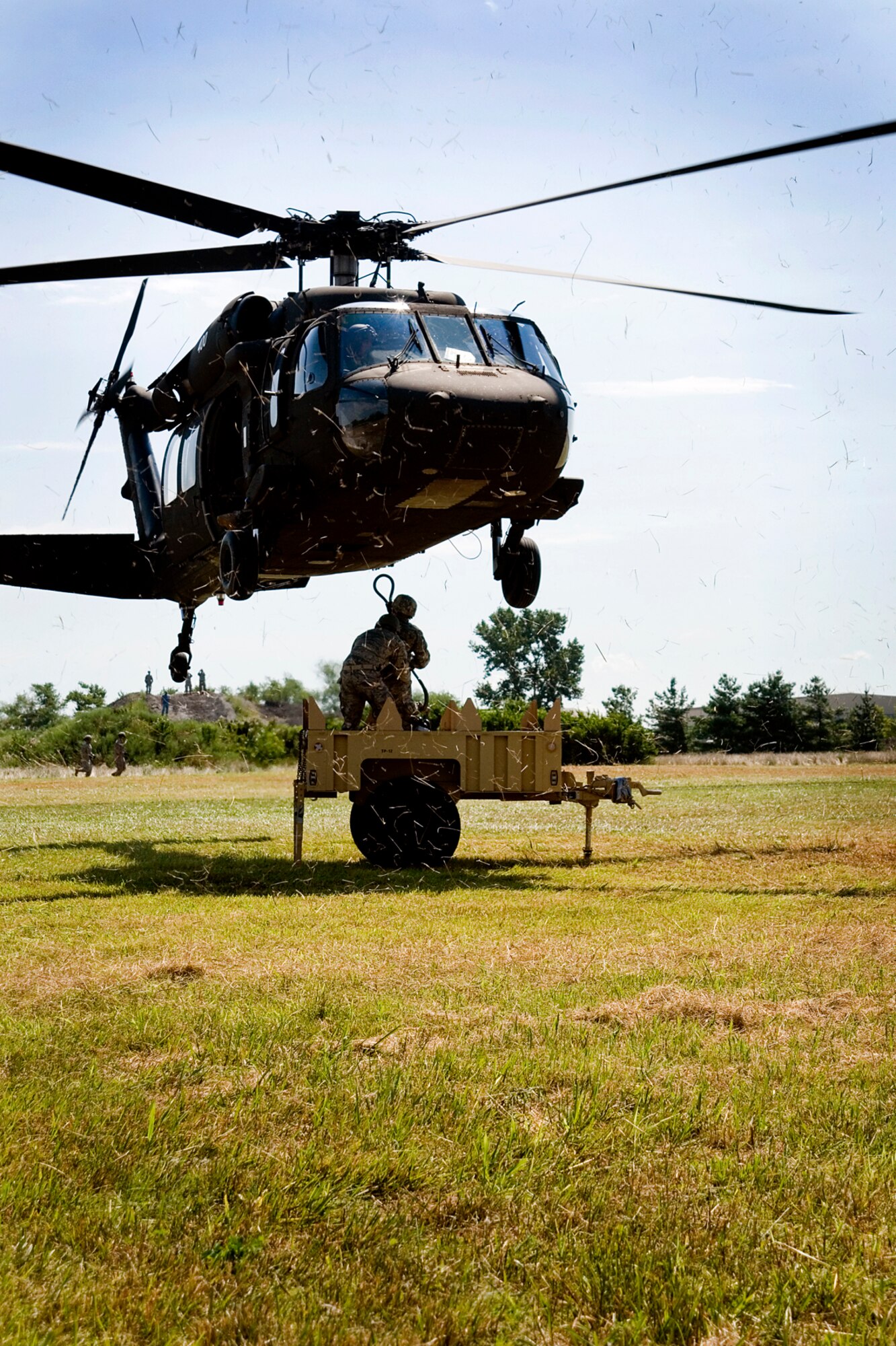 Senior Airman Matthew Stone, 434th Force Support Squadron services specialist, raises a hooking pendant to a UH-60 Black Hawk helicopter as part of sling load training. Stone is anchored by Tech. Sgt. Roland Benitez. (U.S. Air Force photo/Tech. Sgt. Douglas Hays)