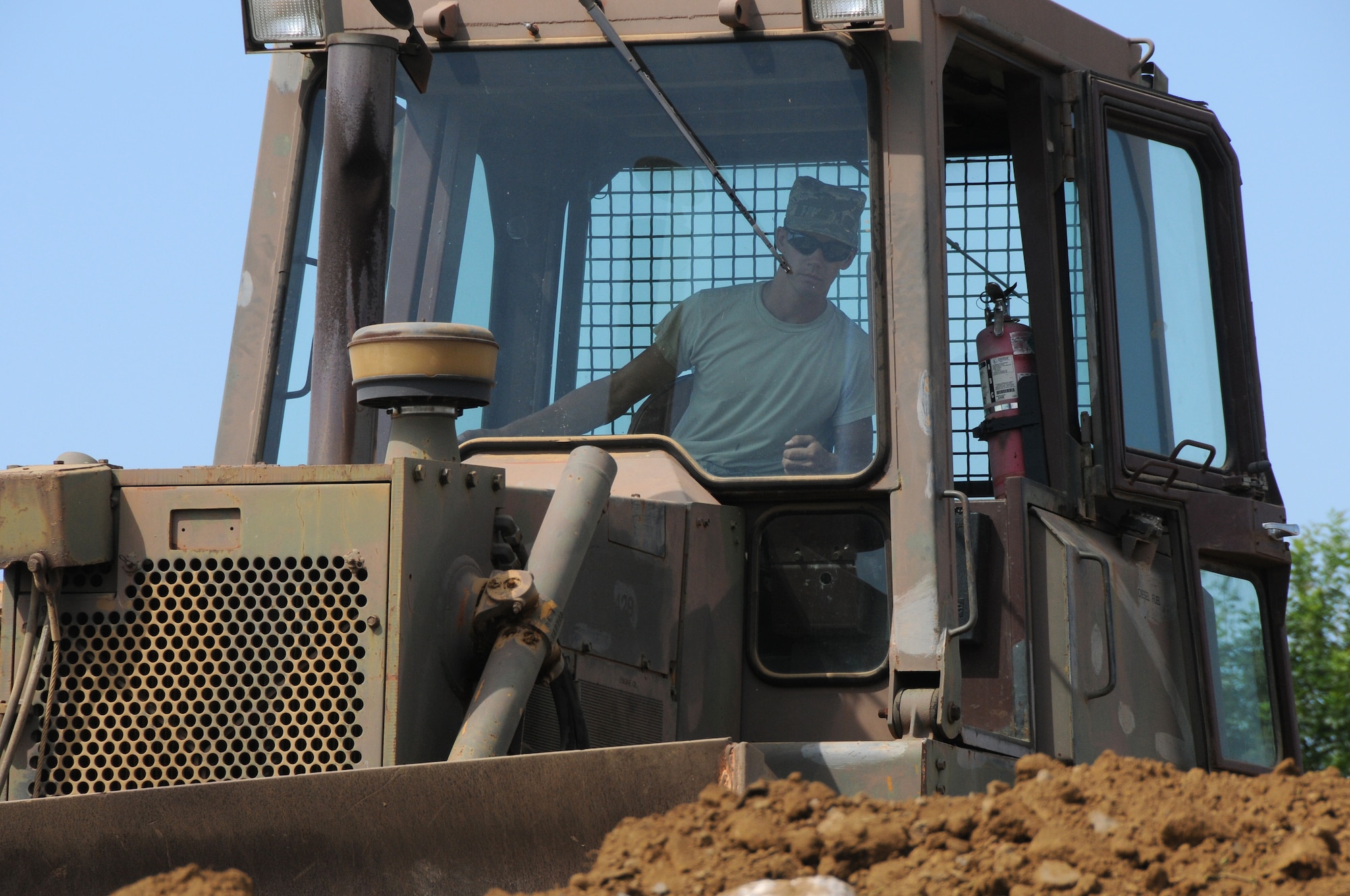 An Airman with the 188th Civil Engineering Squadron levels earth with a bulldozer at the 188th's urban search and rescue training facility, July 11, 2013. CES Airmen are expanding the facility's capacity and making improvements at the site. (U.S. Air National Guard photo by Senior Airman John Hillier/188th Fighter Wing Public Affairs.)
