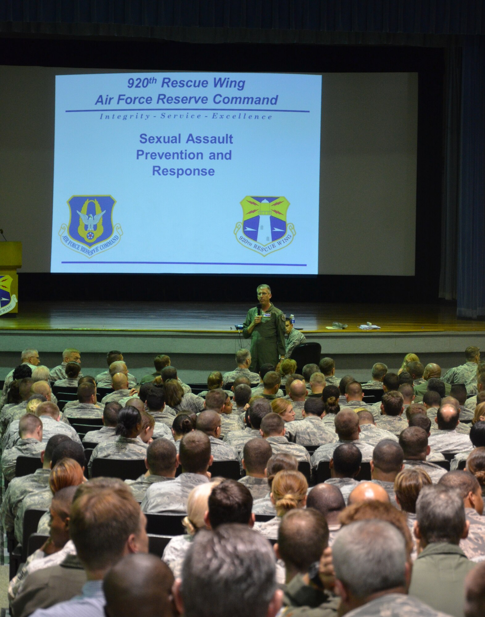 Col. Jeffrey Macrander, 920th Rescue Wing commander, addresses his Rescue Wing Warriors prior to handing the mic to Lt. Col. Michele Leone for a sexual assault prevention and response presentation during their unit training assembly Aug. 4. Leone discussed the differences between sexual harassment and sexual assault, as well as outlets in which the Rescue Airmen can report any misconduct. The purpose of the briefing was to educate and discuss the issue of sexual harassment and sexual assault in the Department of Defense in conjunction with completing an annual training requirement. (U.S. Air Force photo/Senior Airman Natasha Dowridge)