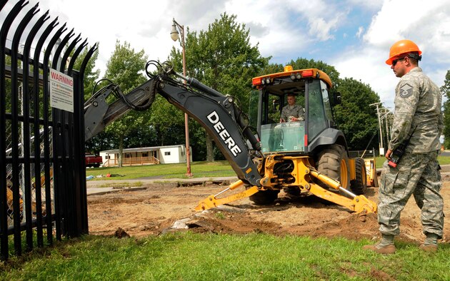 Master Sgt. Kevin E. Hughes watches as Senior Airman Bradley J. Hunt operates a John Deere backhoe to repair a road at Pease Air National Guard Base, N.H., August 3, 2013.  Both Airmen are assigned to the 157th Civil Engineering Squadron here at Pease.  (U.S. Air National Guard photo by Staff Sgt. Curtis J. Lenz/RELEASED)