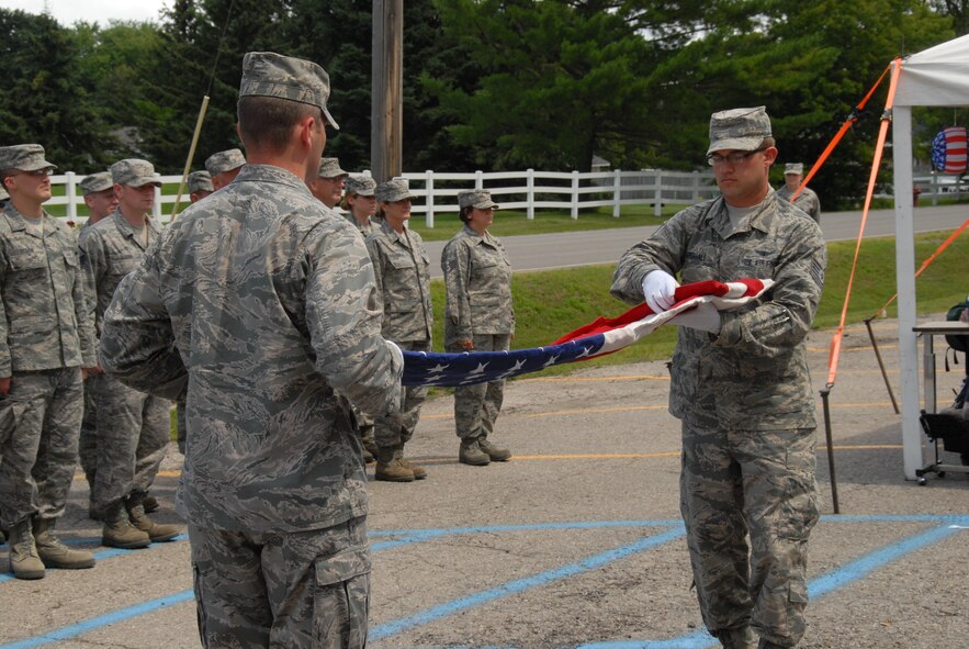 2nd Lt. Peter Herrmann, left, 126th Intelligence Squadron, and Tech. Sgt. Benjamin Marshall, 126th Intelligence Squadron, Ohio Air National Guard, fold a flag during a flag retirement ceremony July 31, 2013 at Alpena, Mich. Herrmann and Marshall participated in the ceremony as public outreach during the annual Alpena, Mich. training exercise. (U.S. Air National Guard photo by Master Sergeant Seth Skidmore/Released)