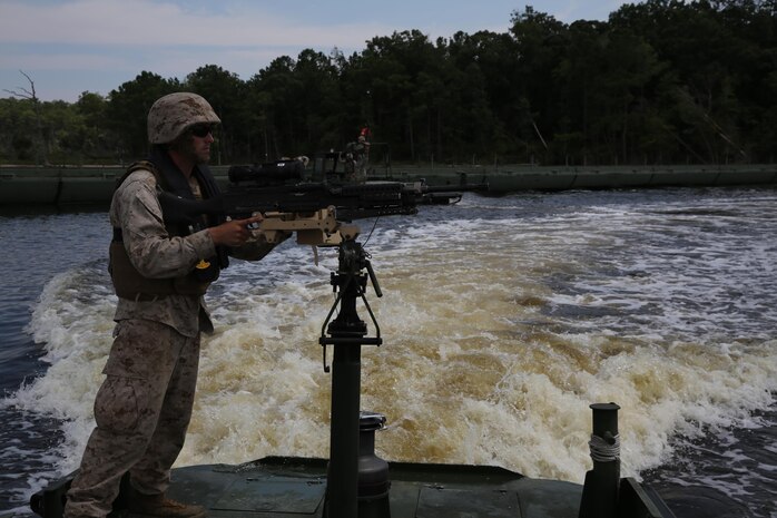 A Marine with Bridge Company, 8th Engineer Support Battalion, 2nd Marine Logistics Group guide provides security on a MK III Bridge Erection Boat while a High Mobility Multipurpose Wheeled Vehicle crosses a continuous span of 43 Improvised Ribbon Bridges during a training exercise at Engineer Point aboard Camp Lejeune, N.C., July 30, 2013. Approximately 44 soldiers with 502nd Multi Role Bridge Company, based at Fort Knox, Ky., worked with Marines to build a continuous span piece-by-piece using MK III BEBs.